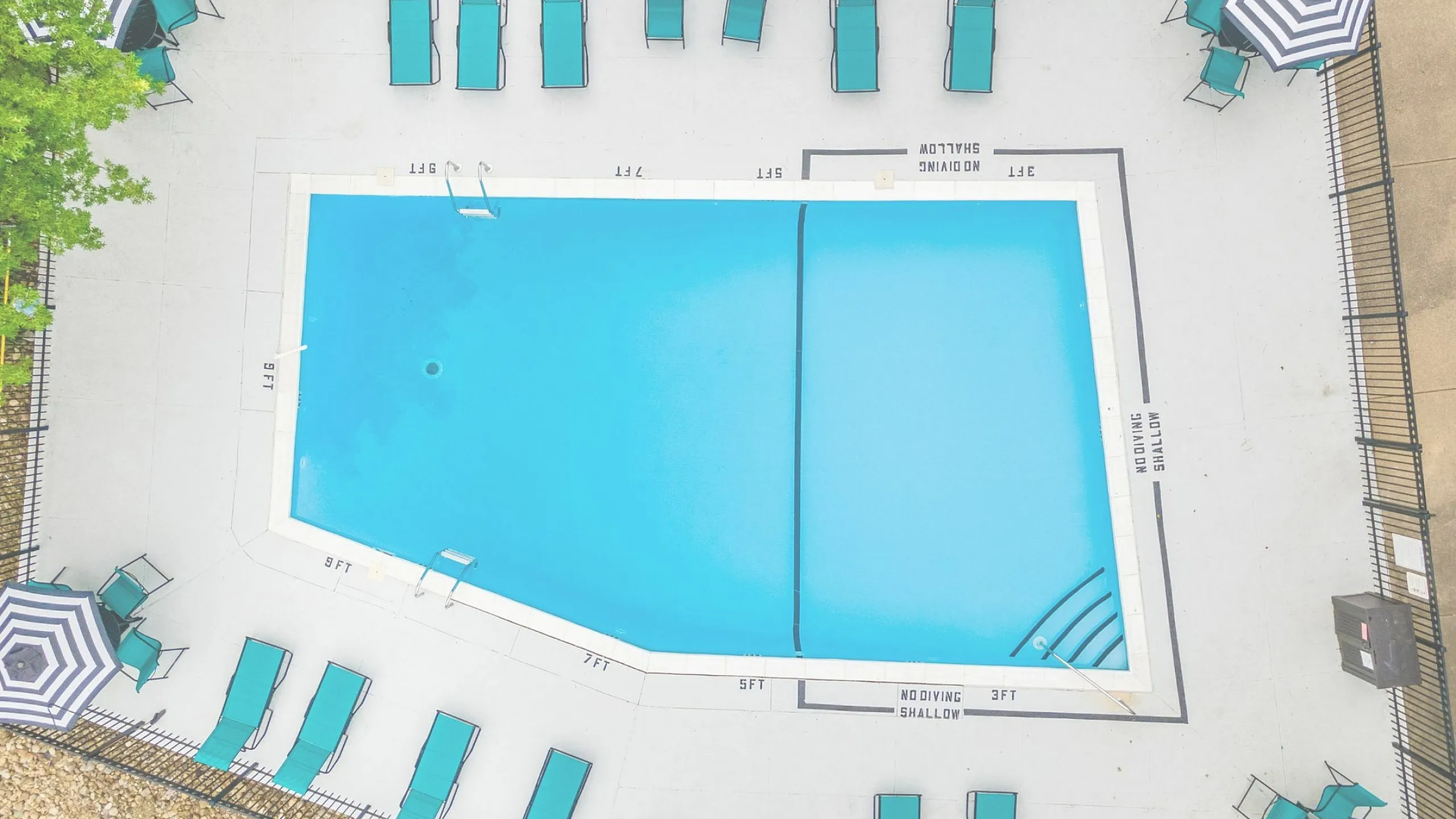 Aerial view of a pristine swimming pool surrounded by stylish teal loungers and umbrellas.