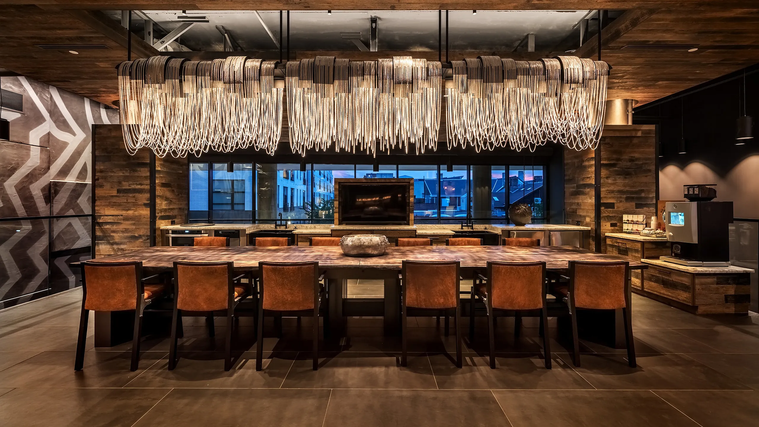 Elegant dining area with a grand chandelier, rustic wood elements, and modern leather seating.