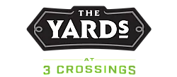 Logo of The Yards at 3 Crossings, featuring bold white lettering on a black geometric background with green accents.