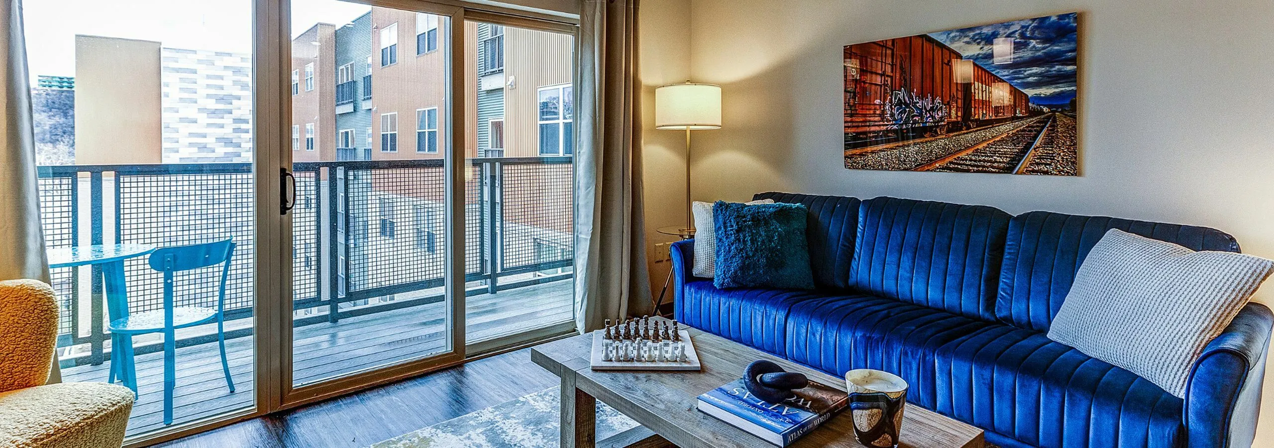 Stylish living room with a plush blue sofa, a modern coffee table, and a balcony view.