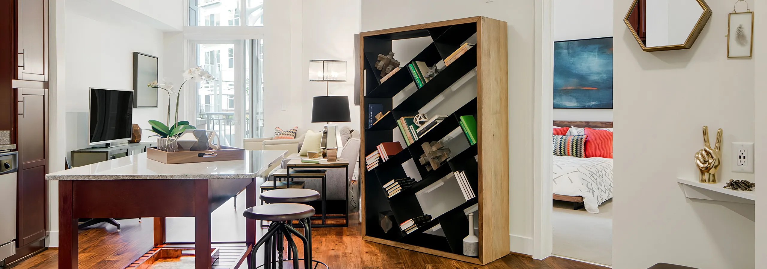 Chic open-concept apartment with a modern kitchen, stylish seating area, and cozy bedroom glimpse.
