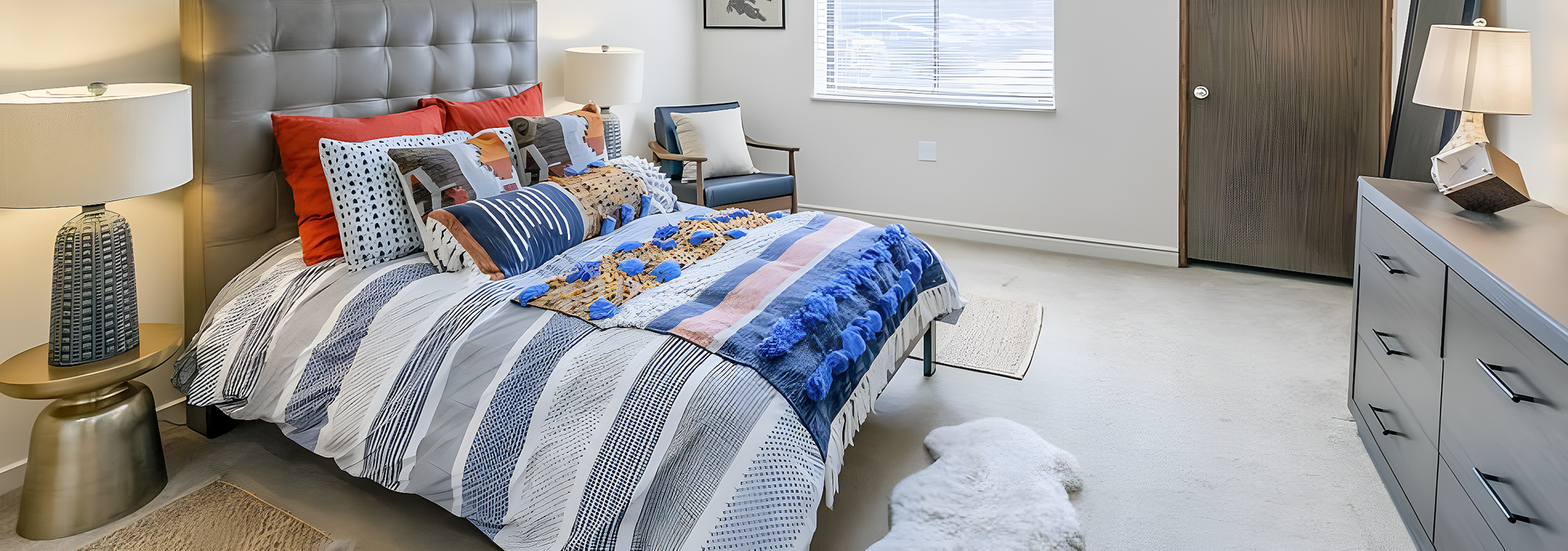 Inviting bedroom featuring a stylish bed with modern decor, elegant lamps, and a soft chair by the window.