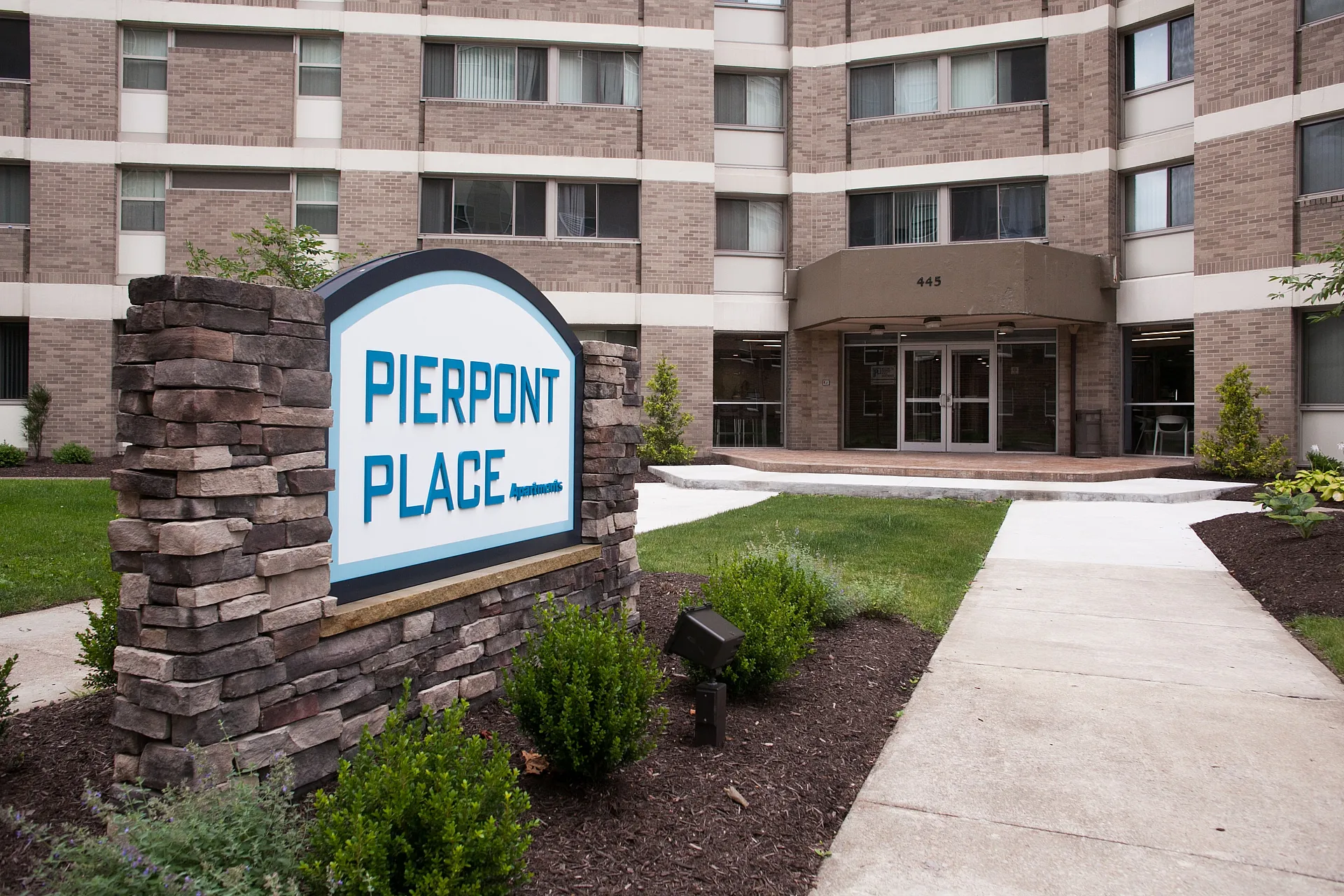 Inviting entrance of Pierpont Place Apartments with modern architecture and landscaped surroundings.