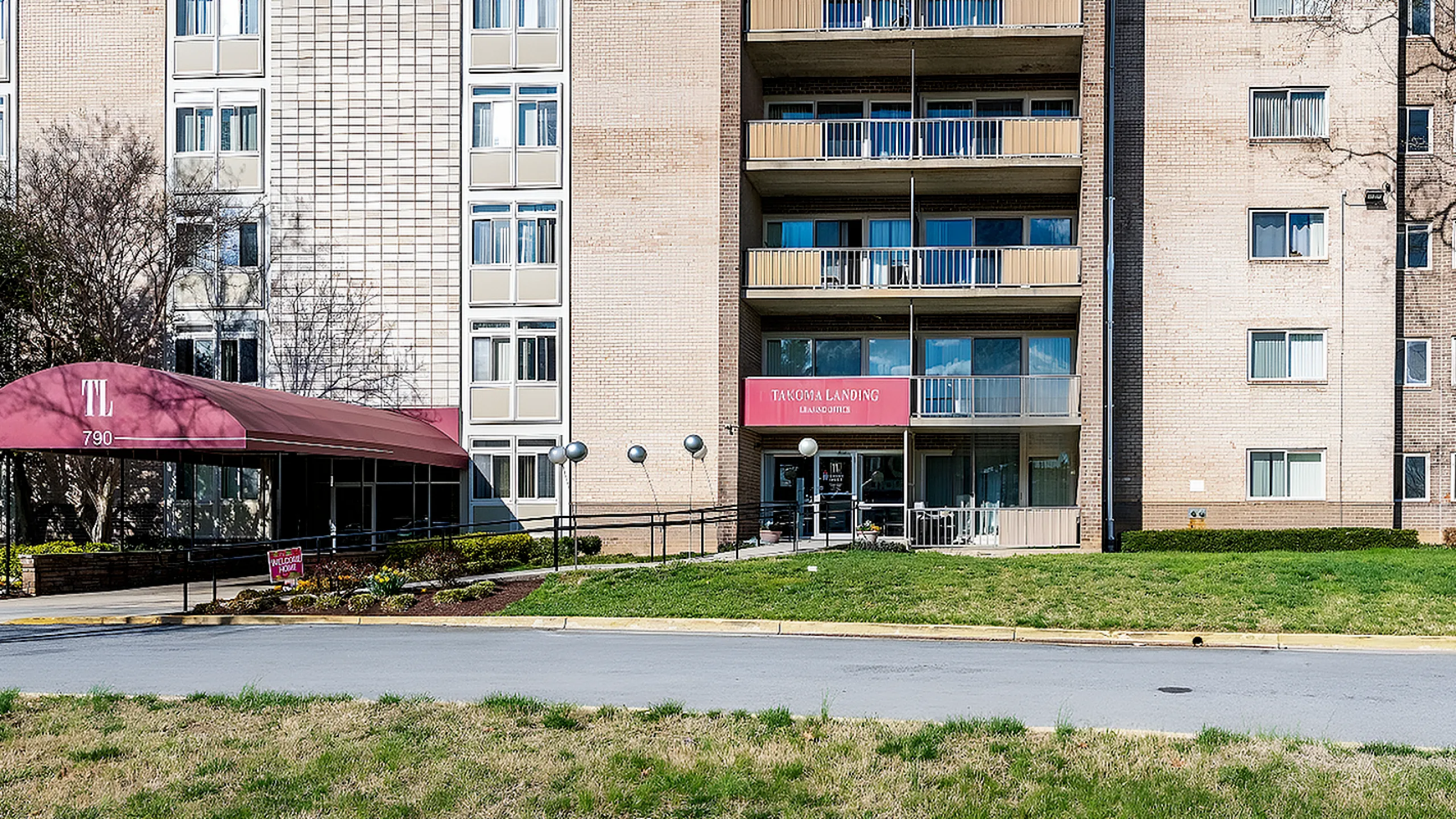 Inviting apartment complex exterior featuring modern architecture with large windows, a welcoming entrance, and lush greenery.