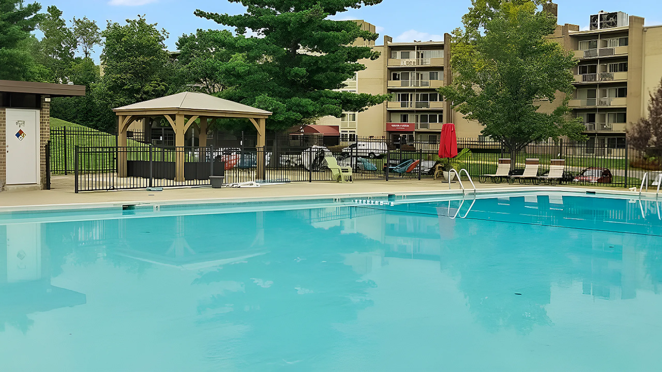 Inviting outdoor pool area with lounge chairs, gazebo, and lush landscaping, perfect for relaxation and leisure.