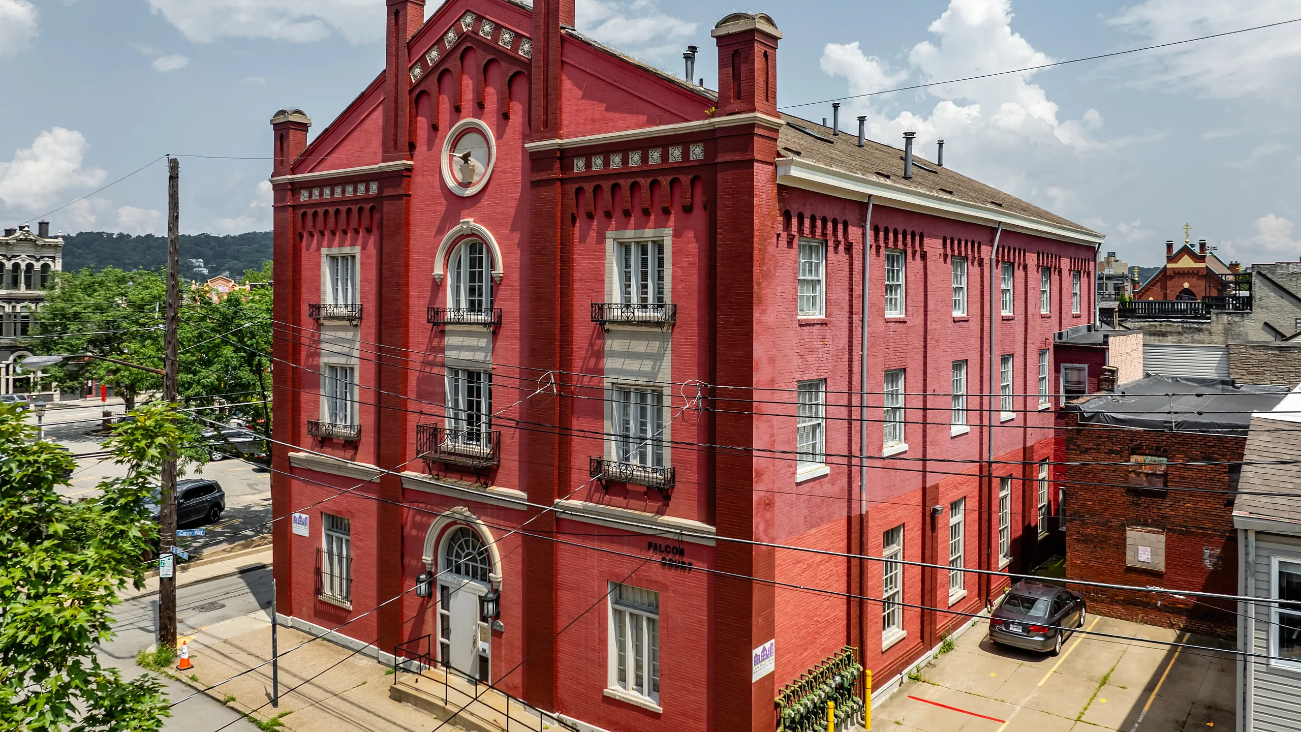 Charming red brick building with classic architecture, featuring arched windows and decorative details, set in a vibrant urban neighborhood.