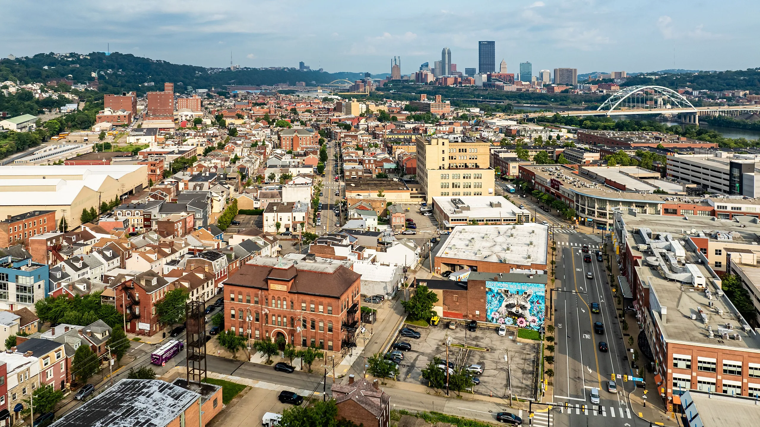 Vibrant cityscape showcasing a bustling urban neighborhood with colorful buildings, a scenic skyline, and iconic bridge in the distance.