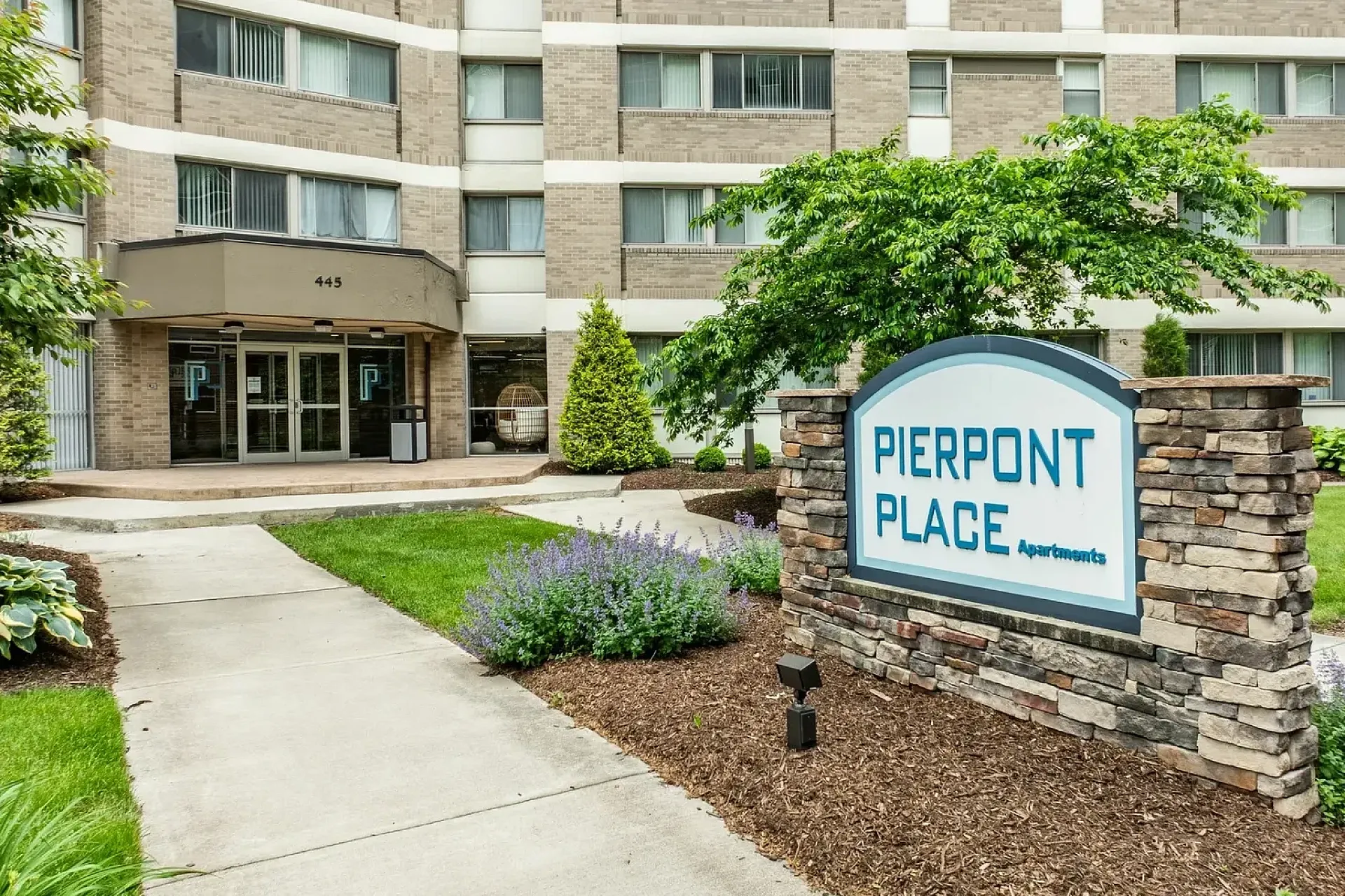 Inviting entrance of Pierpont Place Apartments with modern architecture and landscaped surroundings.