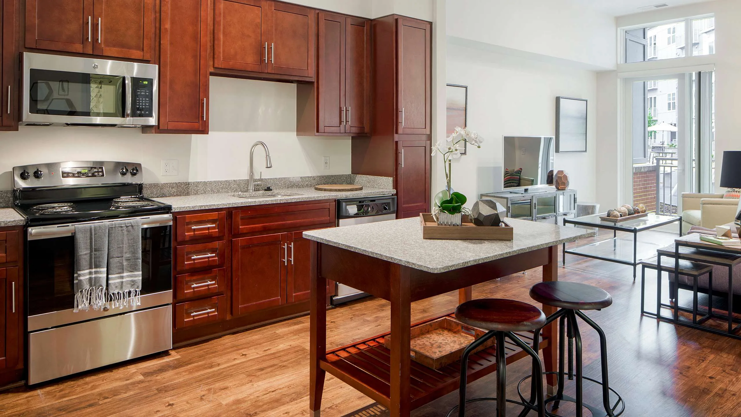 Chic open-concept kitchen and living room with elegant wood cabinets, modern appliances, and stylish bar seating.