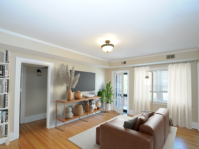 Bright and inviting living room with elegant decor, featuring a plush leather sofa, tasteful shelving, and large windows allowing ample natural light.