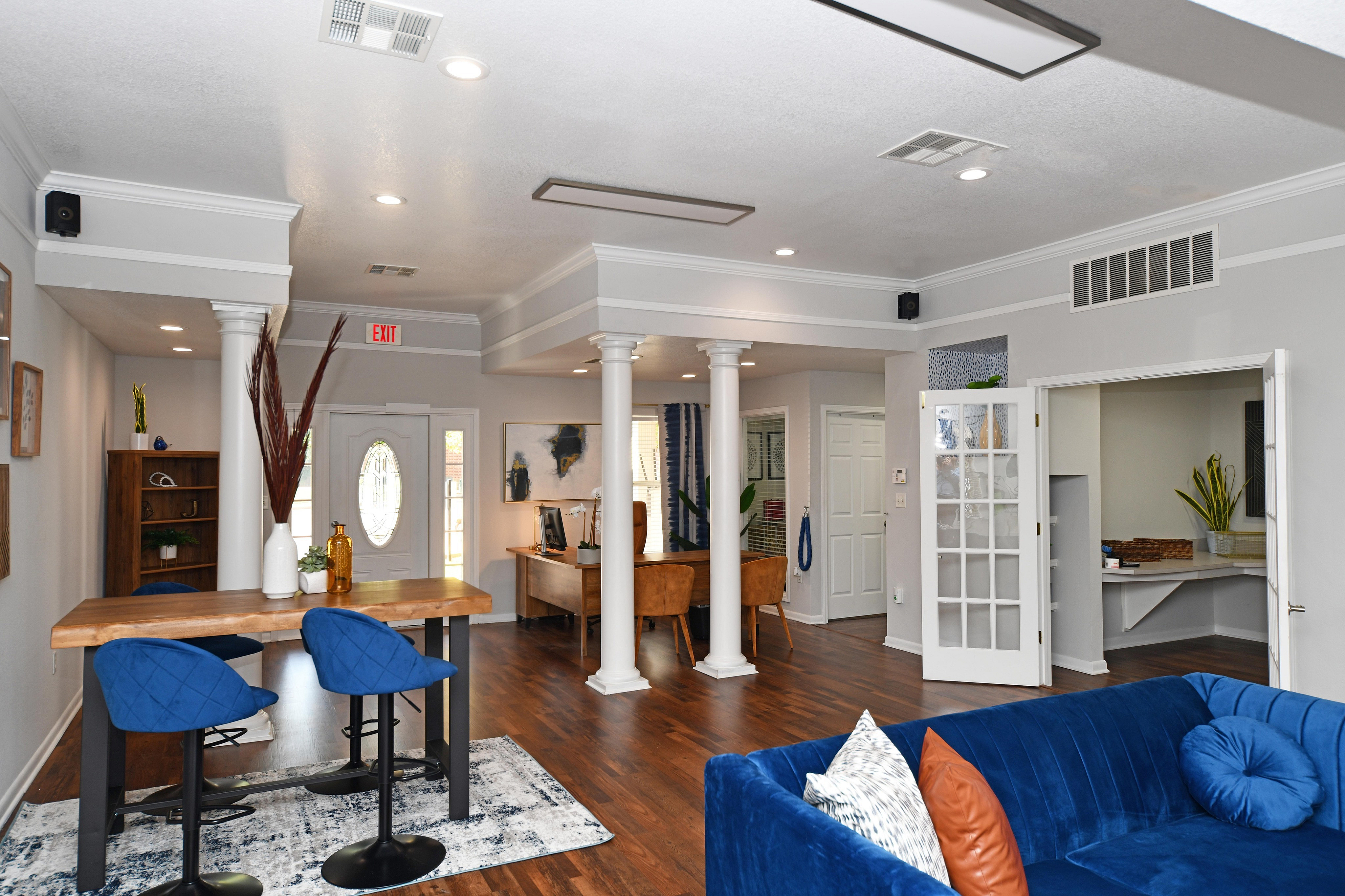 Contemporary open-plan living area with a wooden dining table, blue chairs, and a comfortable seating arrangement.