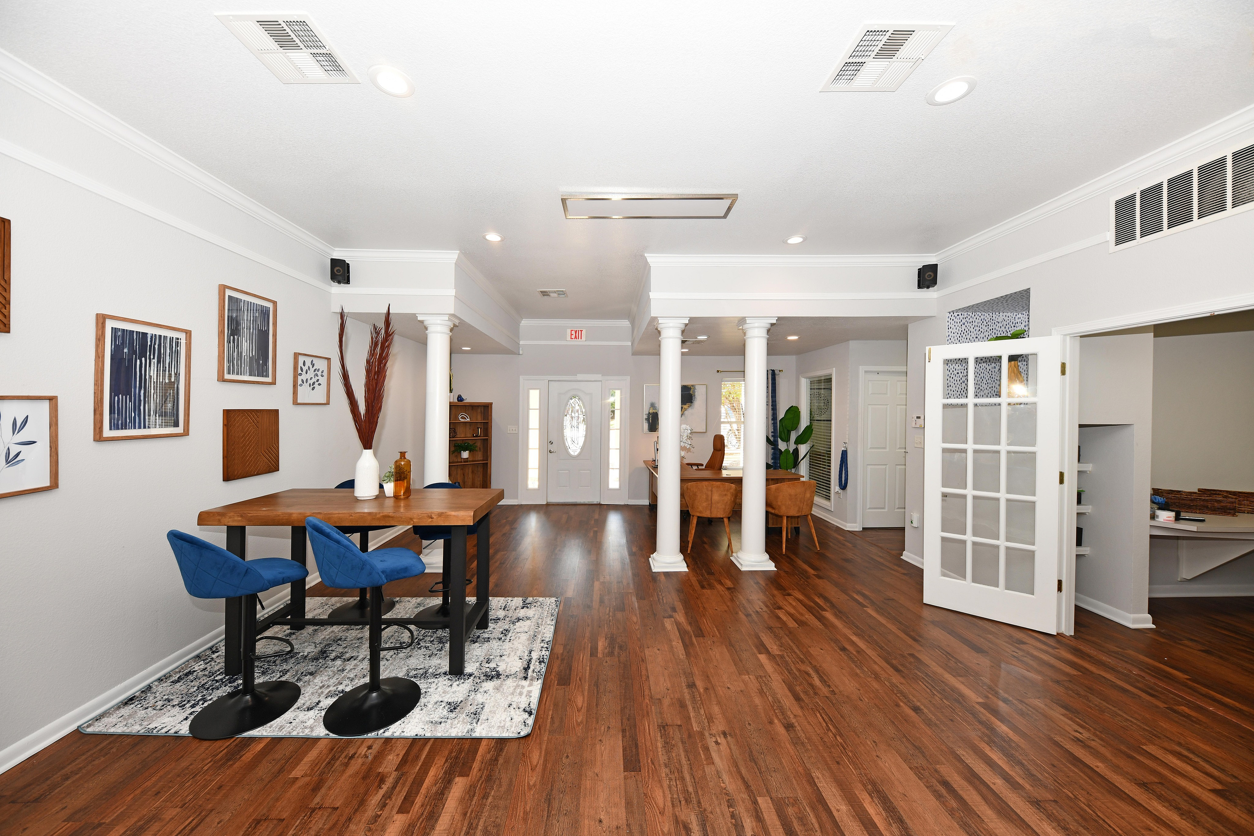 Modern apartment interior with chic décor, featuring a stylish wooden table, blue chairs, and decorative wall art.