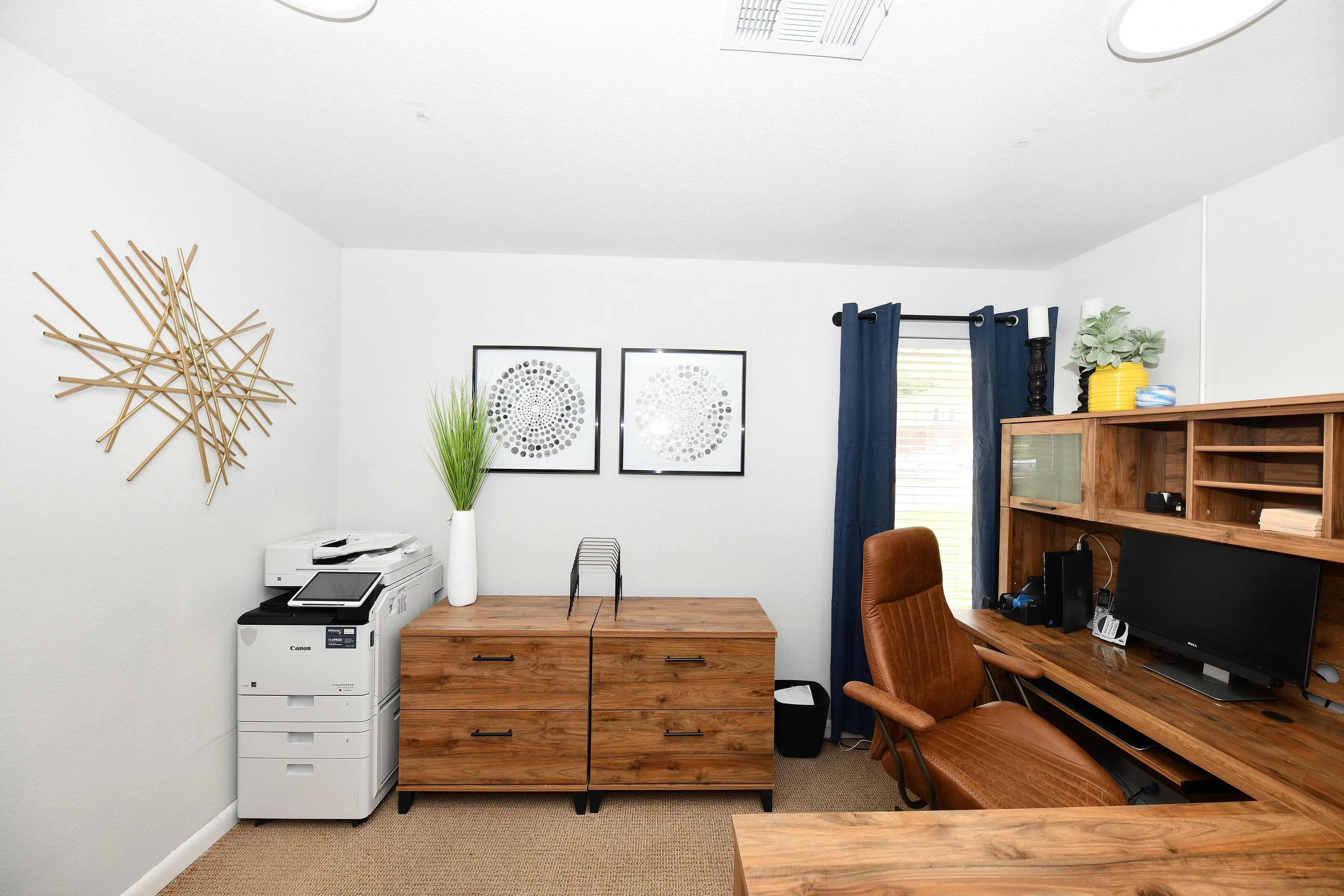 Modern home office with wooden furniture, leather chair, and artistic wall decor.