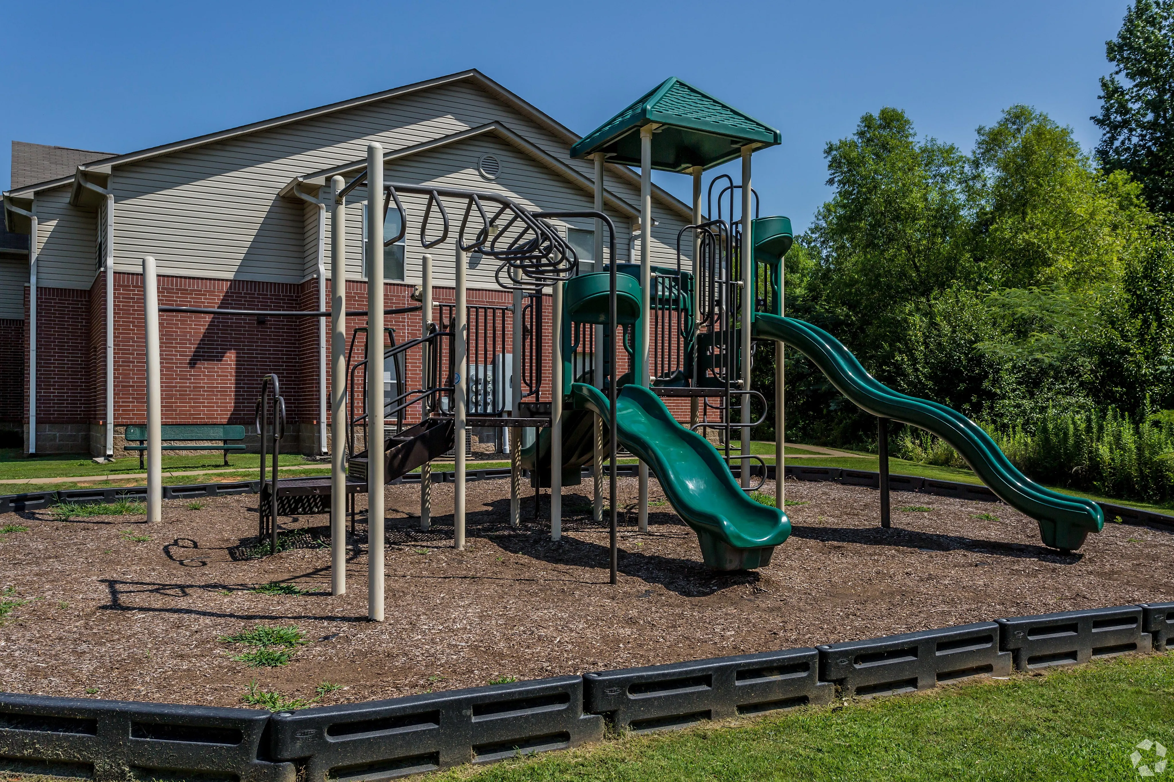 Charming playground with slides and monkey bars in a lush green community environment.