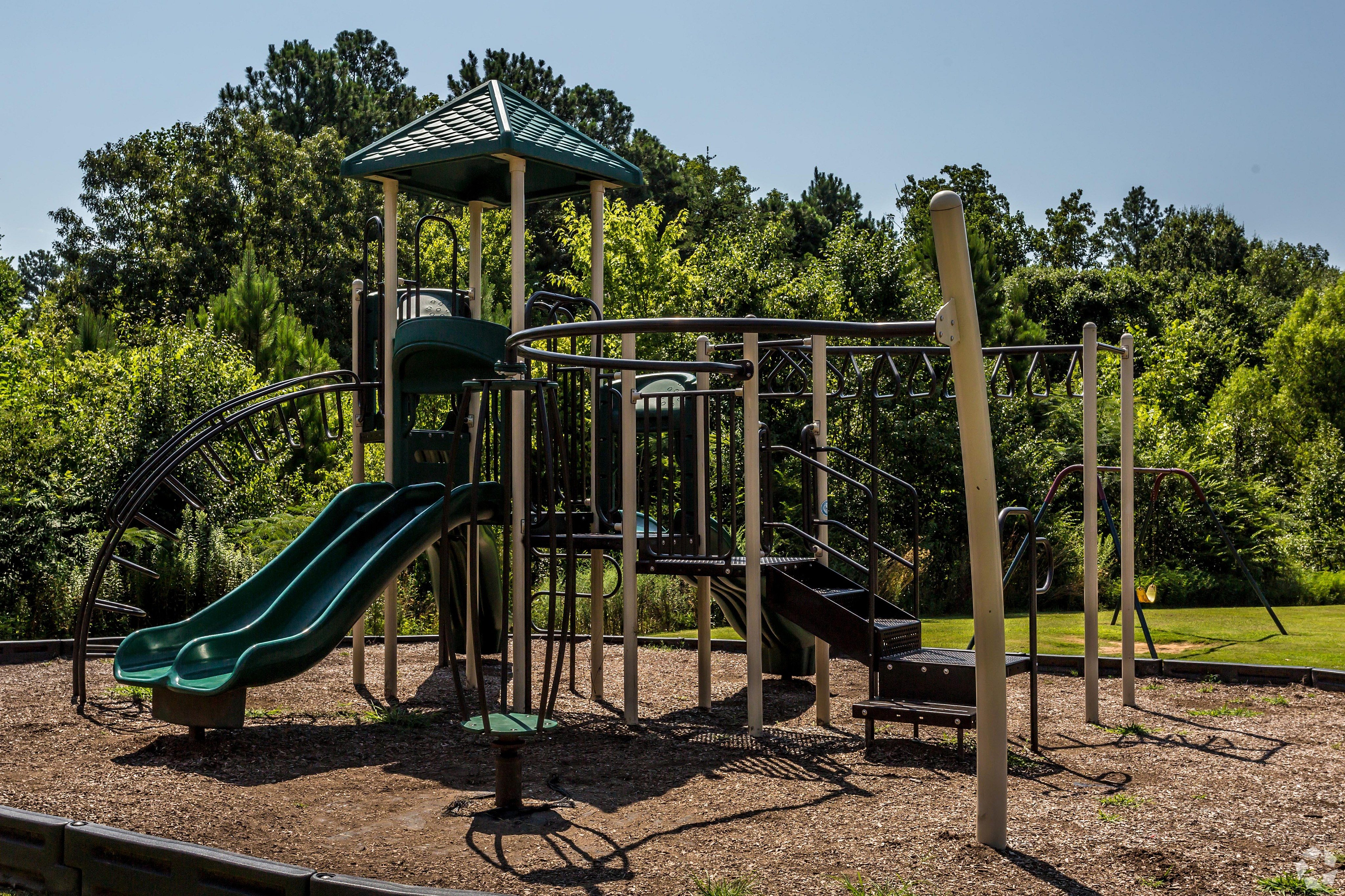 Inviting playground with slides and climbing structures surrounded by lush greenery.