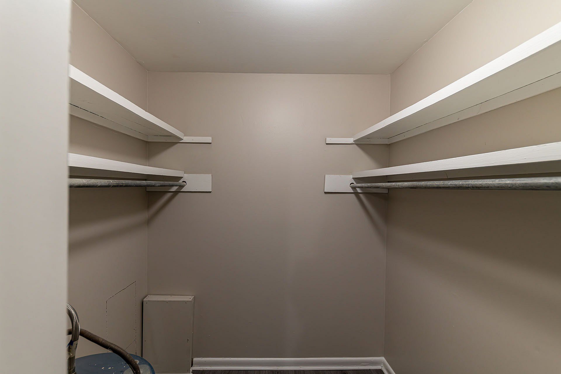 A roomy walk-in closet with multiple shelves and clothing rods, offering ample storage space.