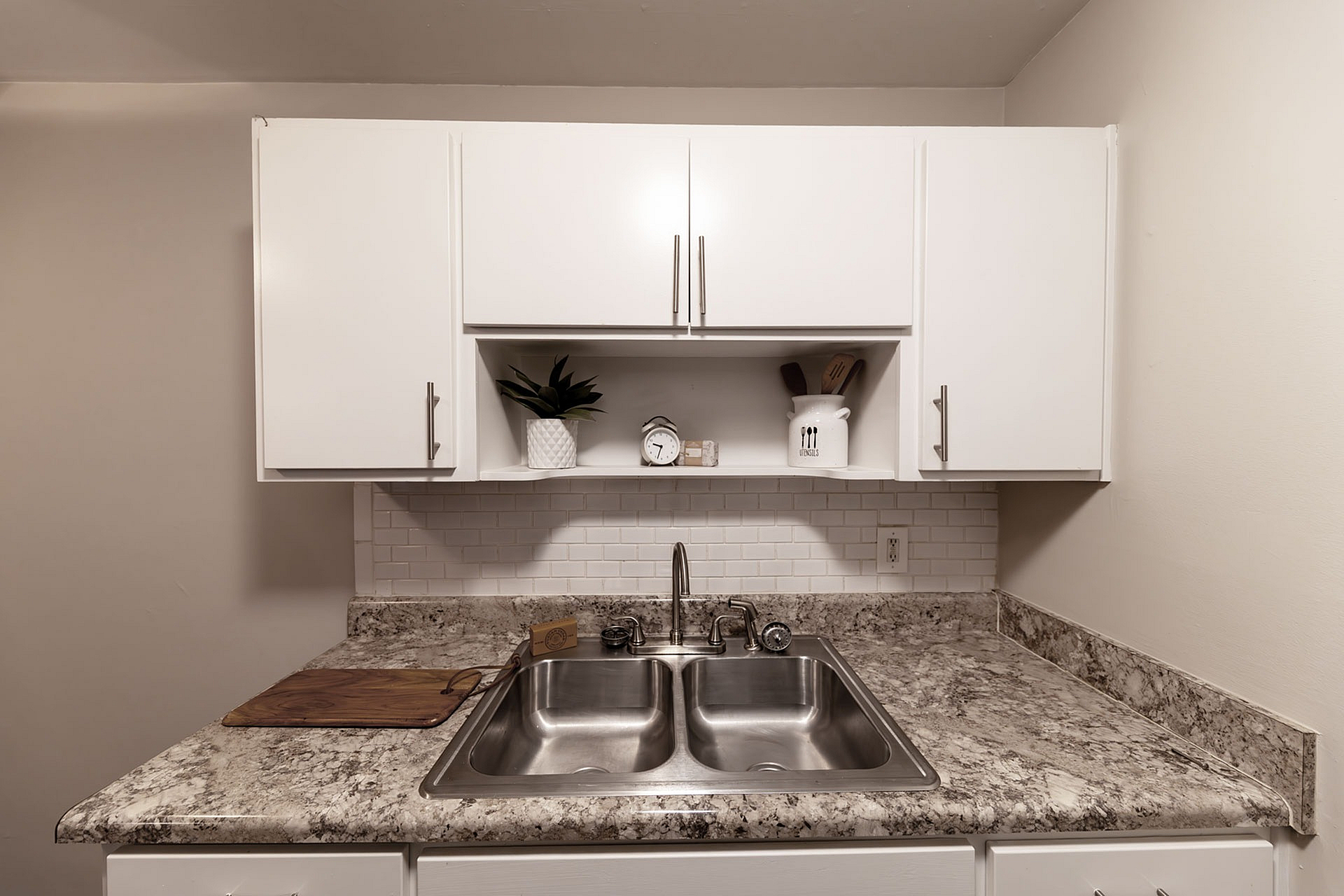 Contemporary kitchen with sleek white cabinets, marble countertops, and modern stainless steel sink.