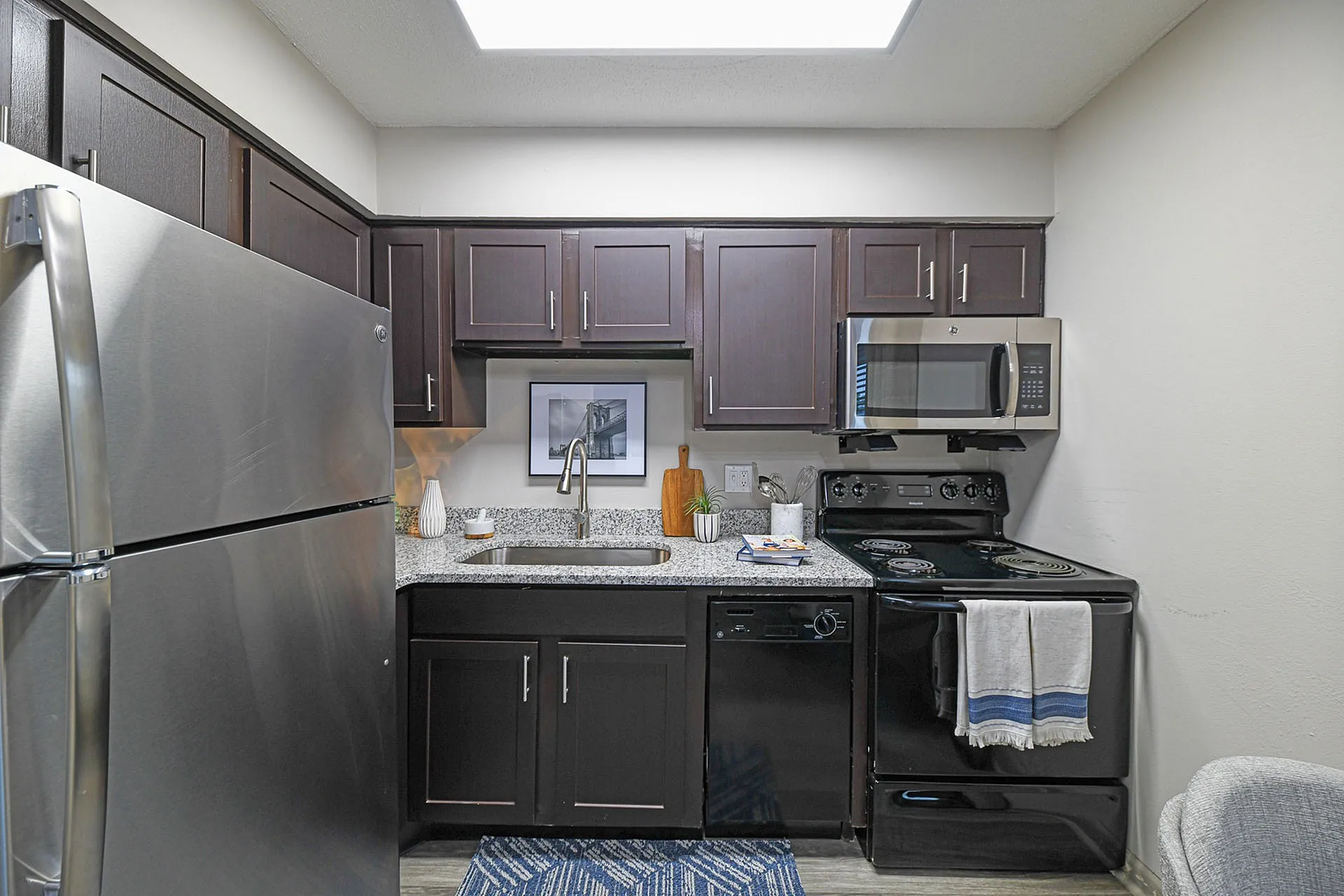 Sleek modern kitchen with dark wood cabinets, stainless steel appliances, and granite countertops.