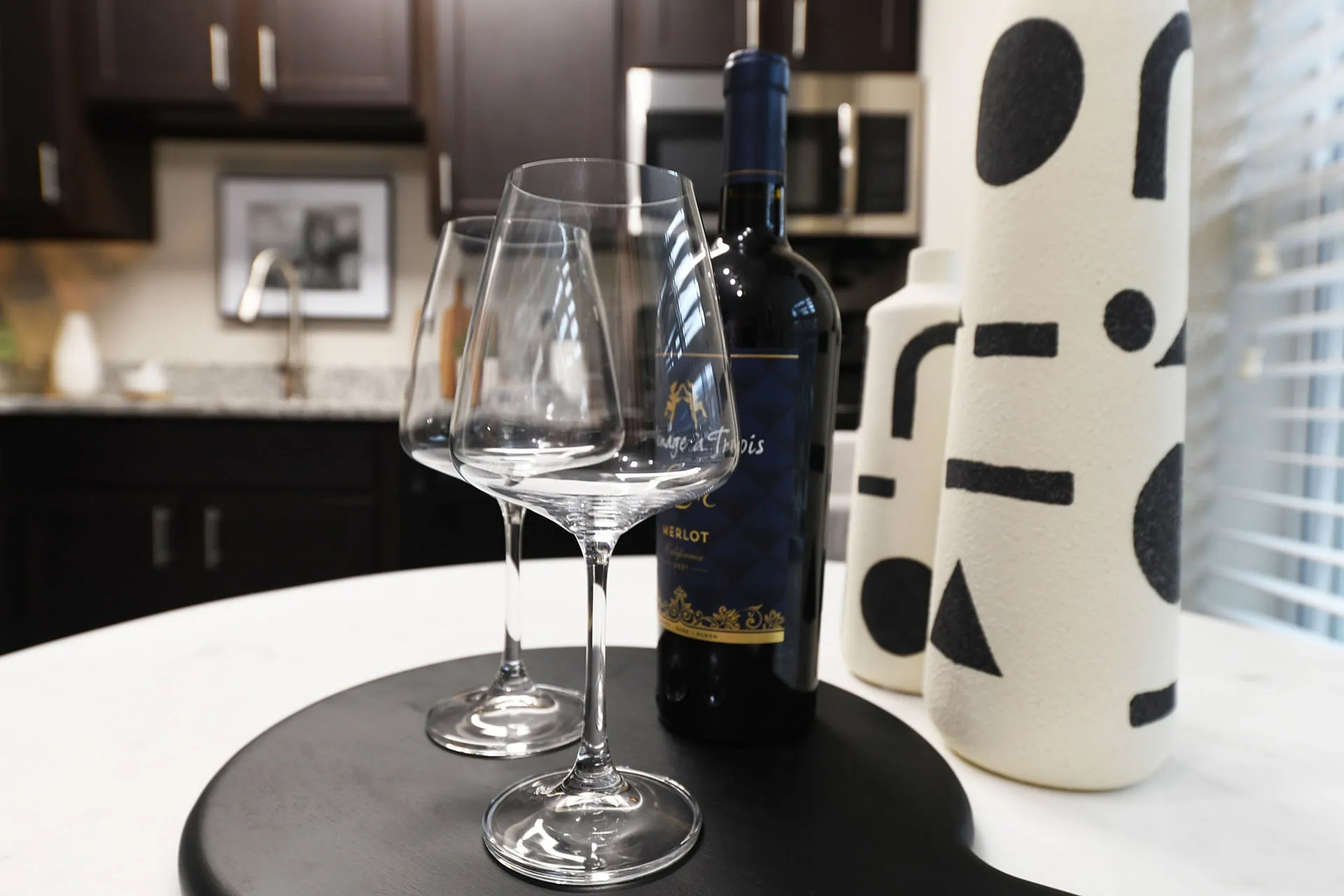 Elegant kitchen setup featuring two wine glasses, a bottle of wine, and modern abstract decor.