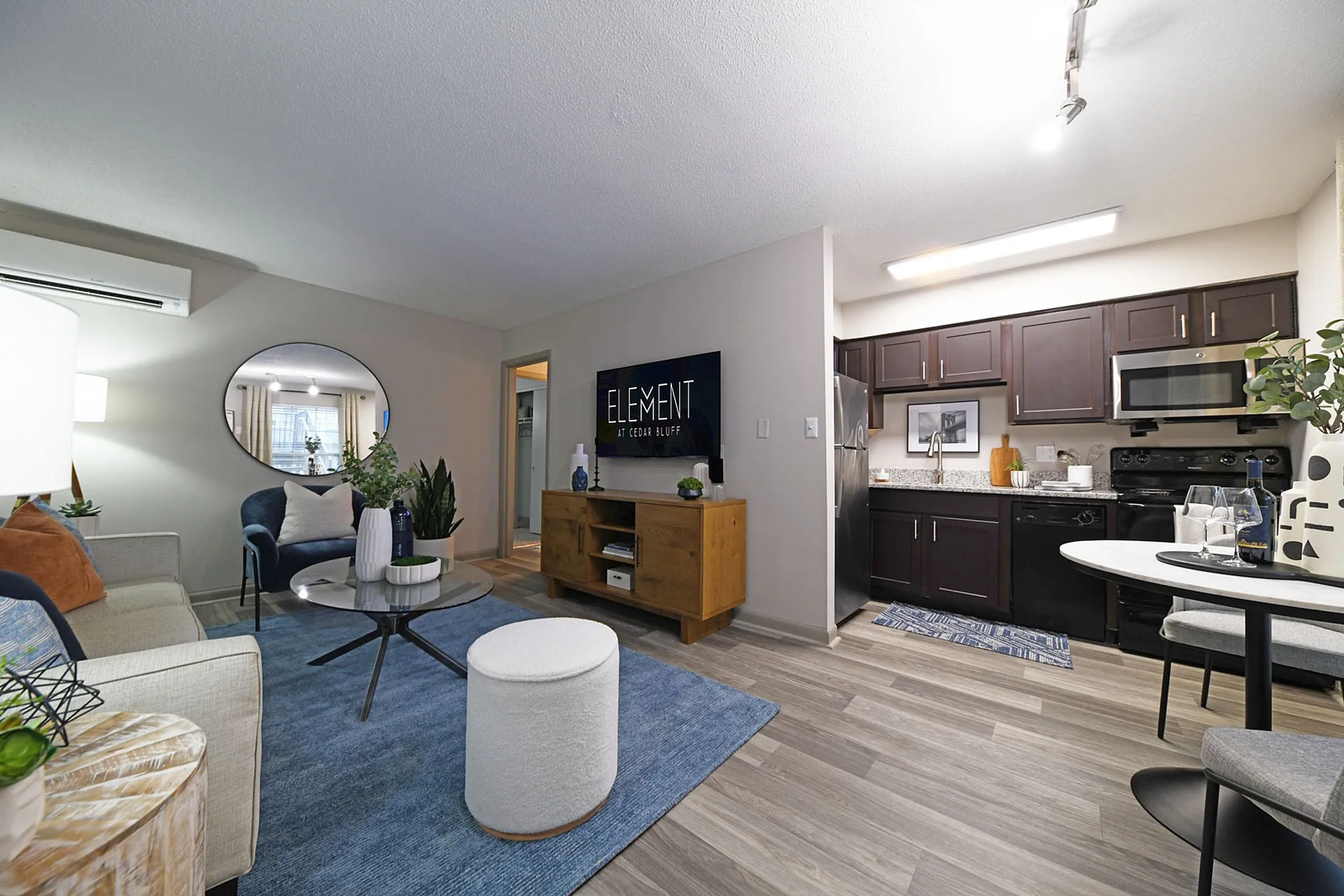 Contemporary apartment living room with chic furniture and a sleek kitchen featuring stainless steel appliances.