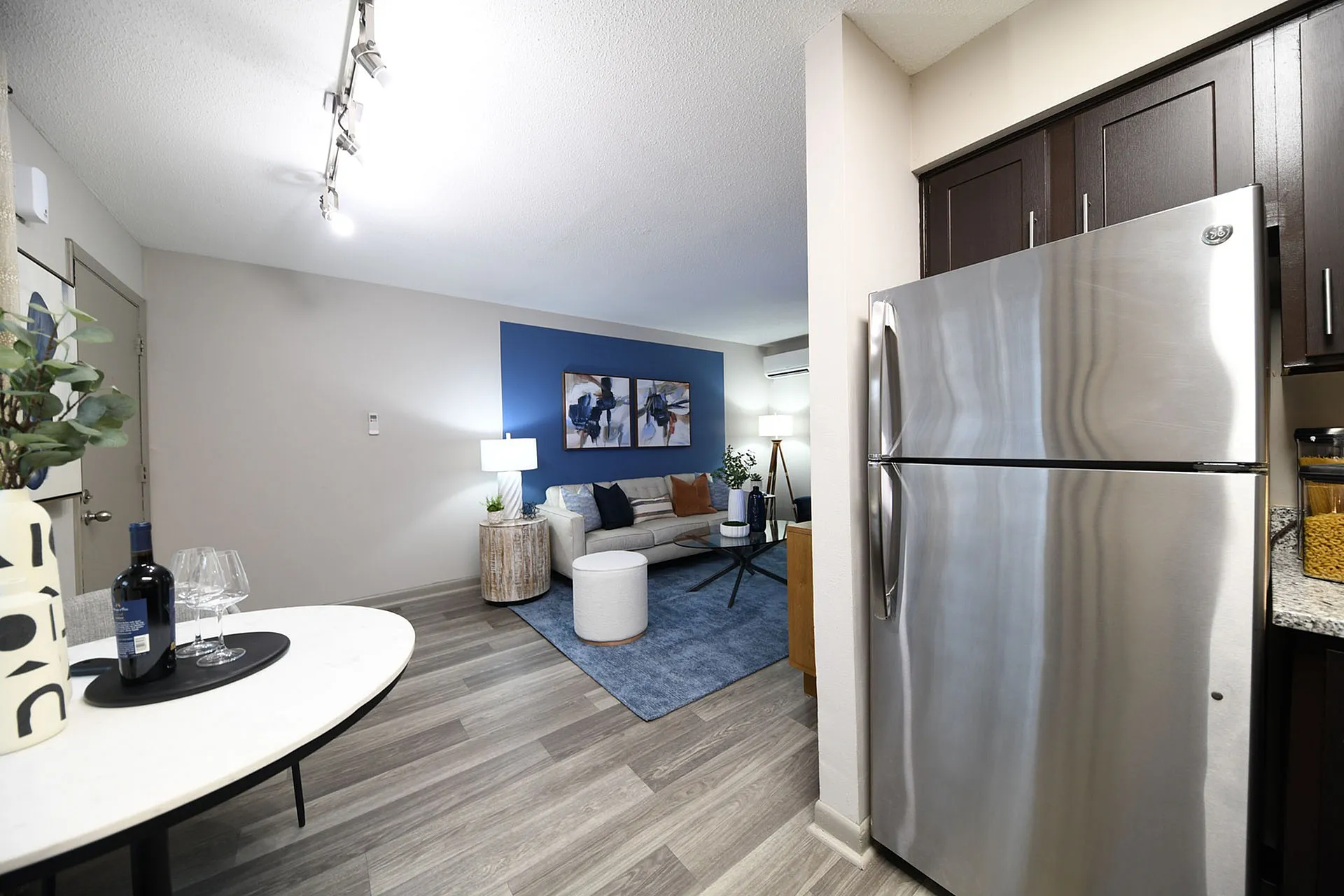 Stylish apartment interior featuring a modern living room with a blue accent wall, cozy seating, and a sleek kitchen area.