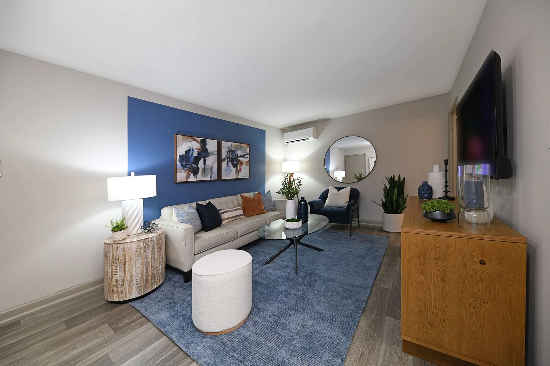 Stylish living room with modern decor, featuring a cozy cream sofa, blue accent wall, and elegant furnishings.