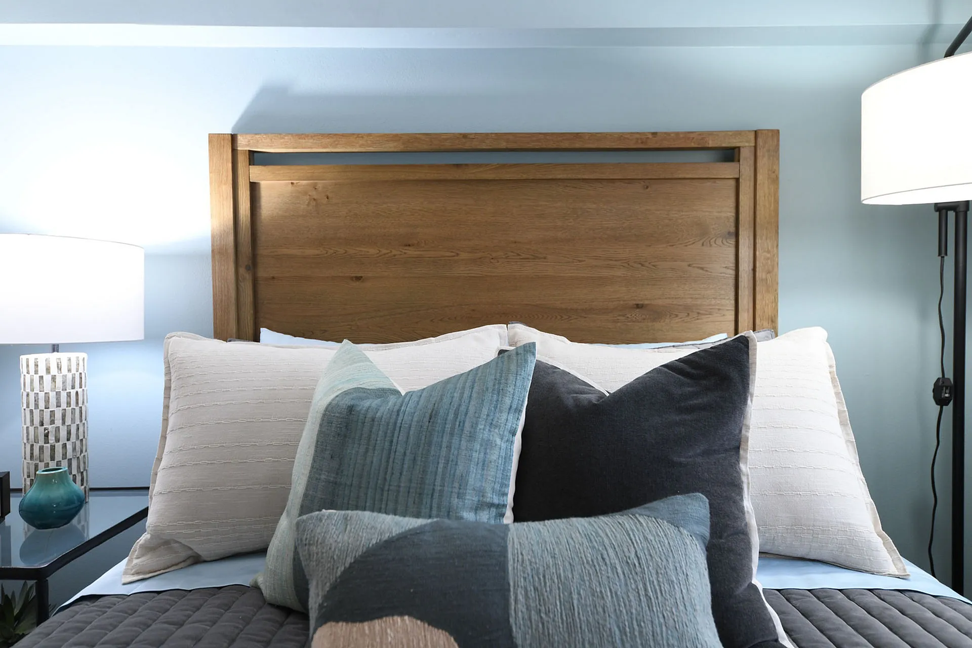 Inviting bedroom with a wooden headboard, plush pillows, and elegant lighting.