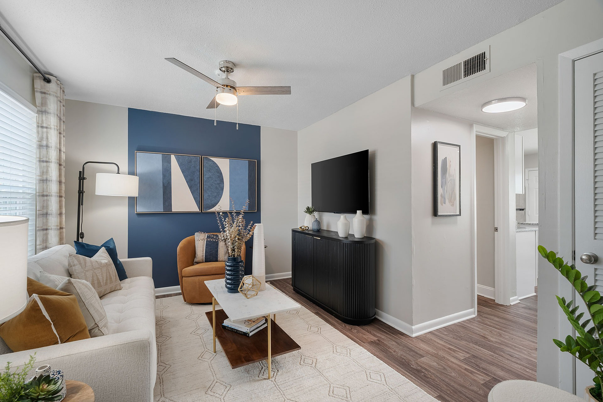 Modern living room with stylish decor, featuring a comfortable sofa, elegant armchair, and abstract wall art in a cozy apartment setting.