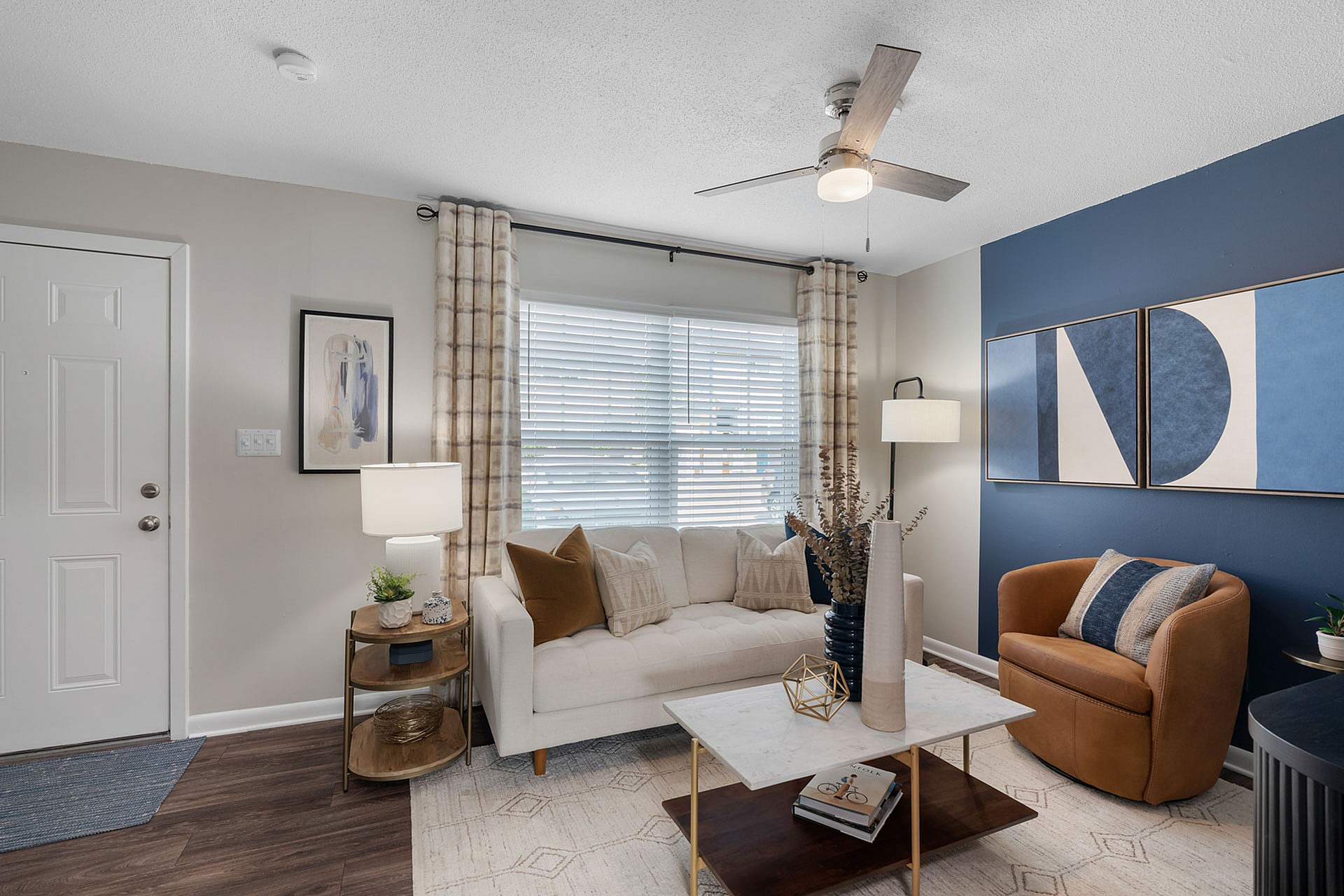 Chic living room with modern decor, cozy seating, and stylish lighting, featuring a bold blue accent wall and elegant art pieces.