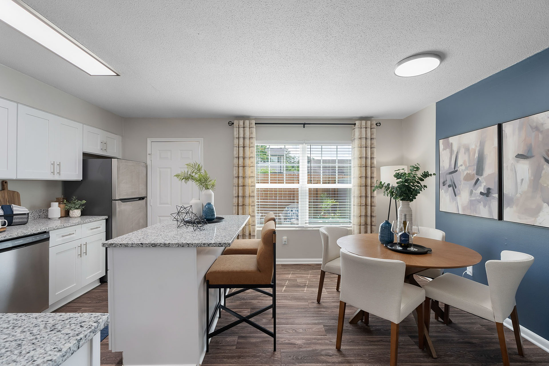 Modern kitchen and dining area featuring granite countertops, stainless steel appliances, and elegant decor with natural light through large windows.