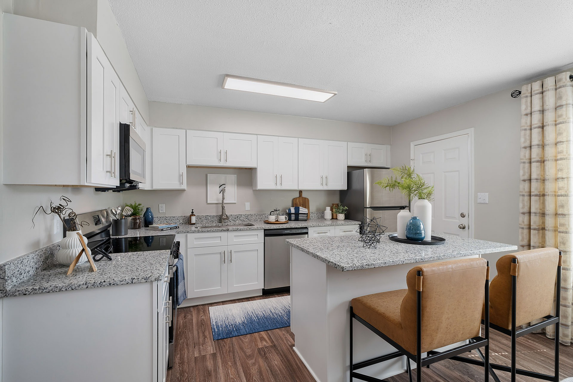 Bright and modern kitchen featuring sleek granite countertops, stylish island seating, and contemporary decor.