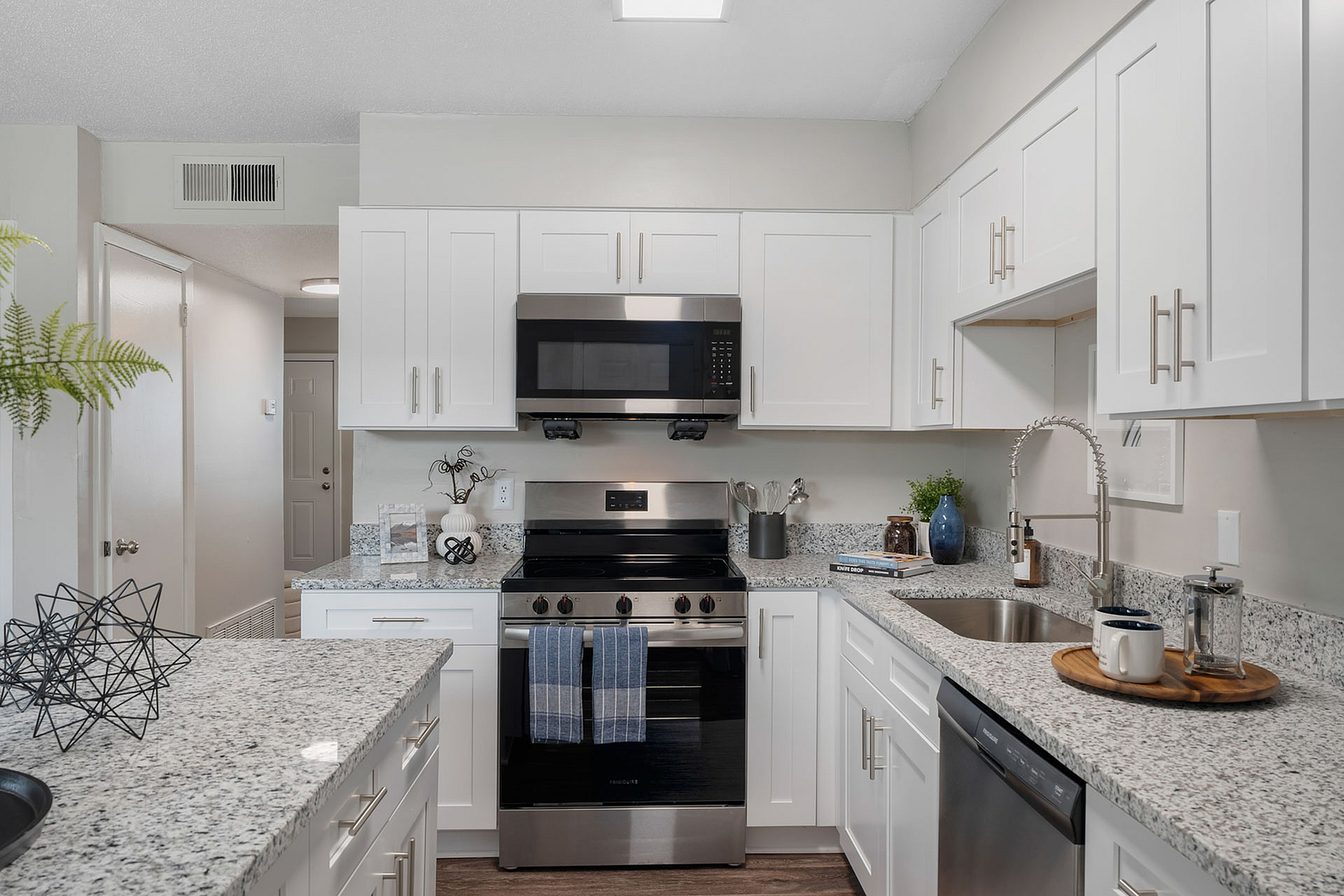 Modern kitchen with sleek granite countertops, stainless steel appliances, and elegant white cabinetry creating a sophisticated cooking space.