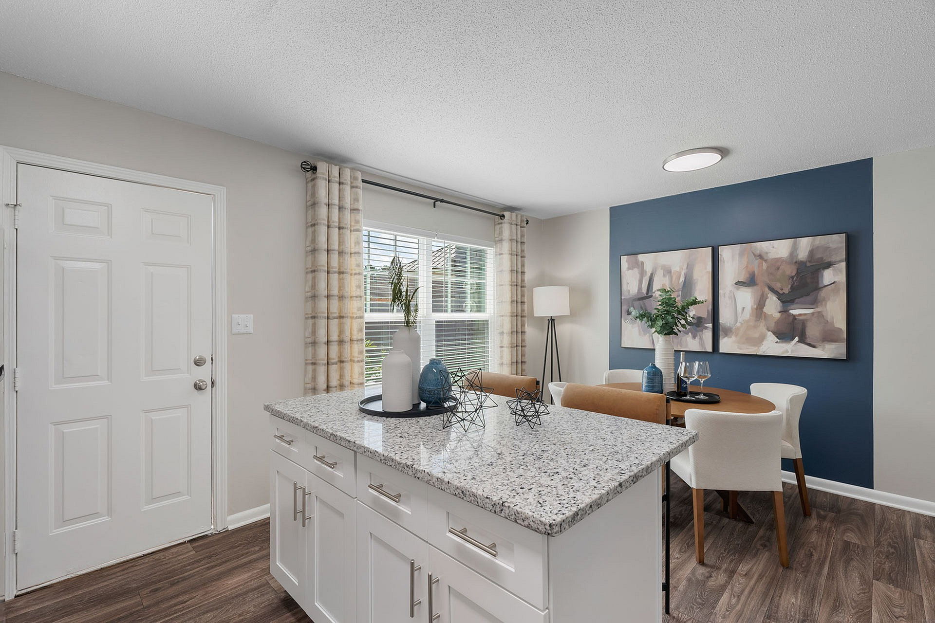 Chic dining area with a sleek granite kitchen island, modern decor, and warm natural light.