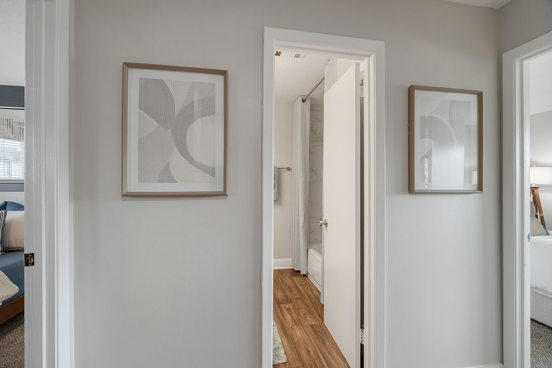 Inviting apartment hallway showcasing elegant decor with framed artwork, leading to cozy bedrooms and a stylish bathroom.