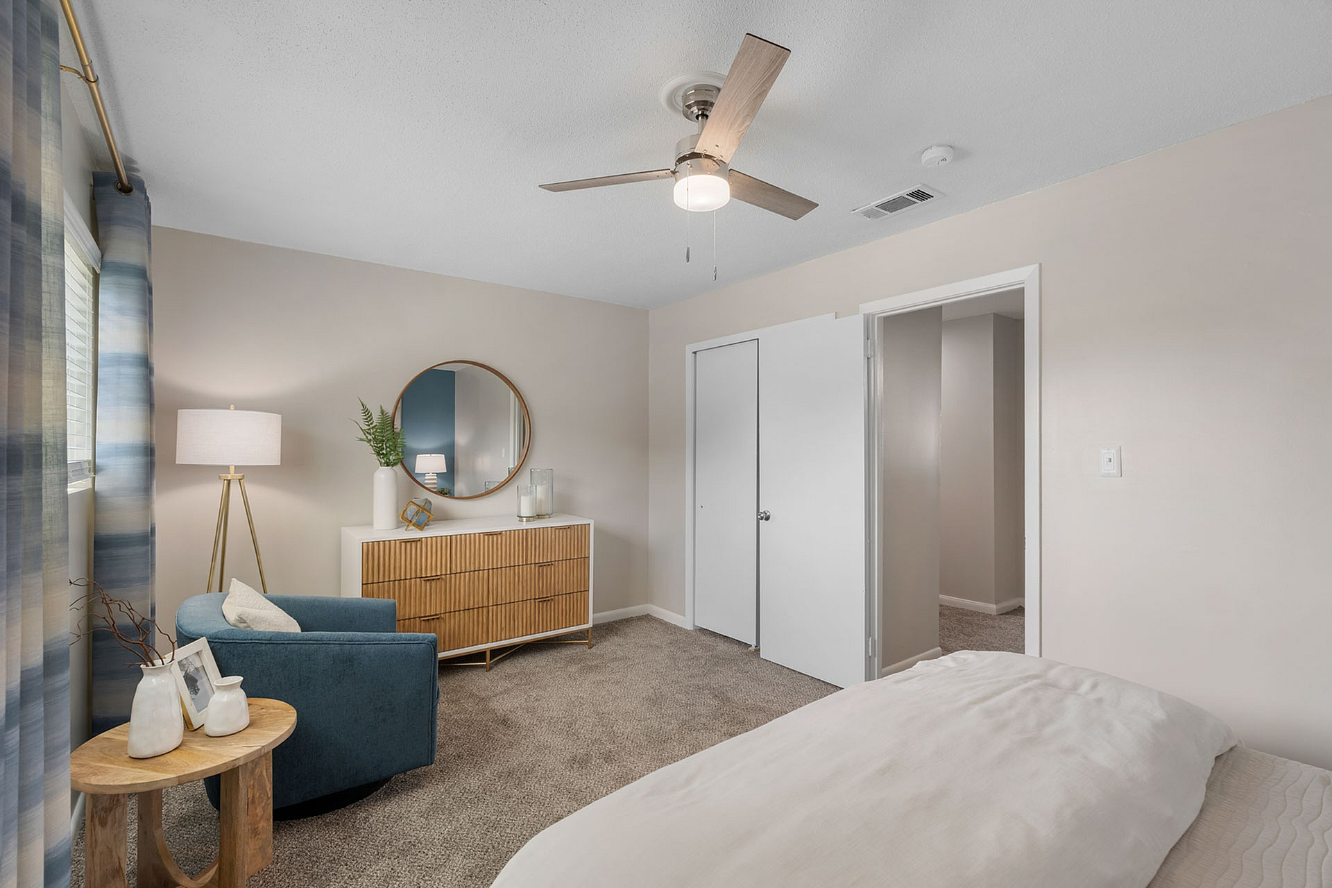 Chic bedroom with cozy seating area, elegant wood dresser, and soft lighting for a serene ambiance.