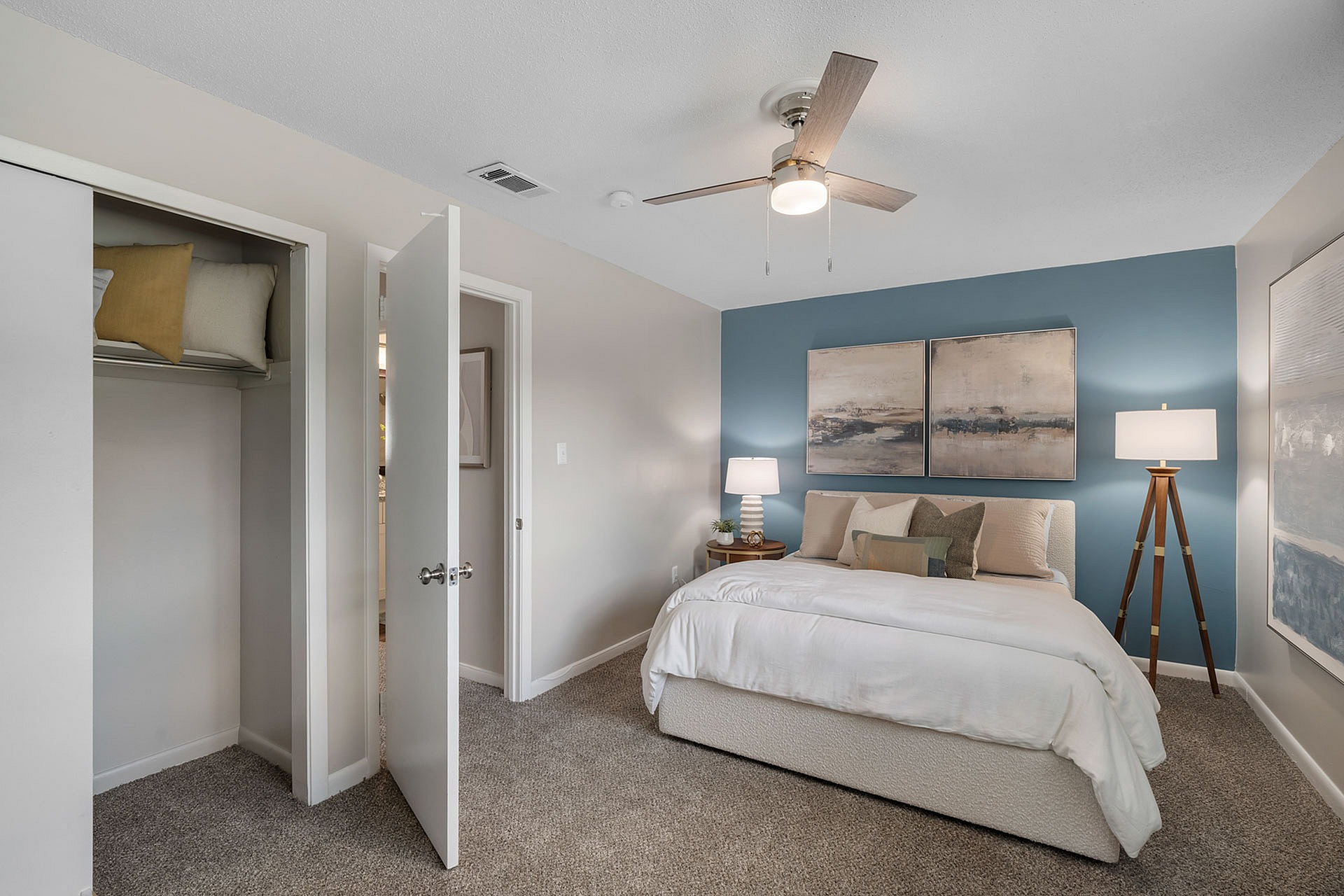 Inviting bedroom with a cozy bed, modern ceiling fan, and elegant decor, perfect for relaxation and comfort.