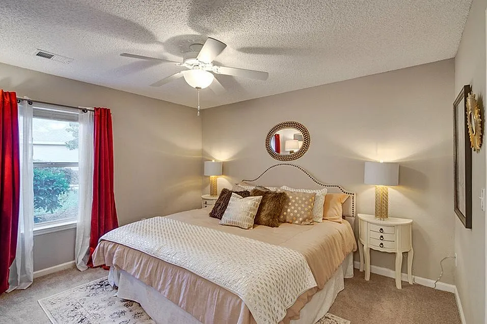 Inviting bedroom with plush bedding, serene lighting, and vibrant red curtains enhancing a cozy atmosphere.