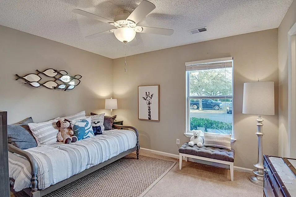 Charming bedroom featuring cozy daybed with plush pillows, elegant wall decor, soft lighting, and a bright window view.