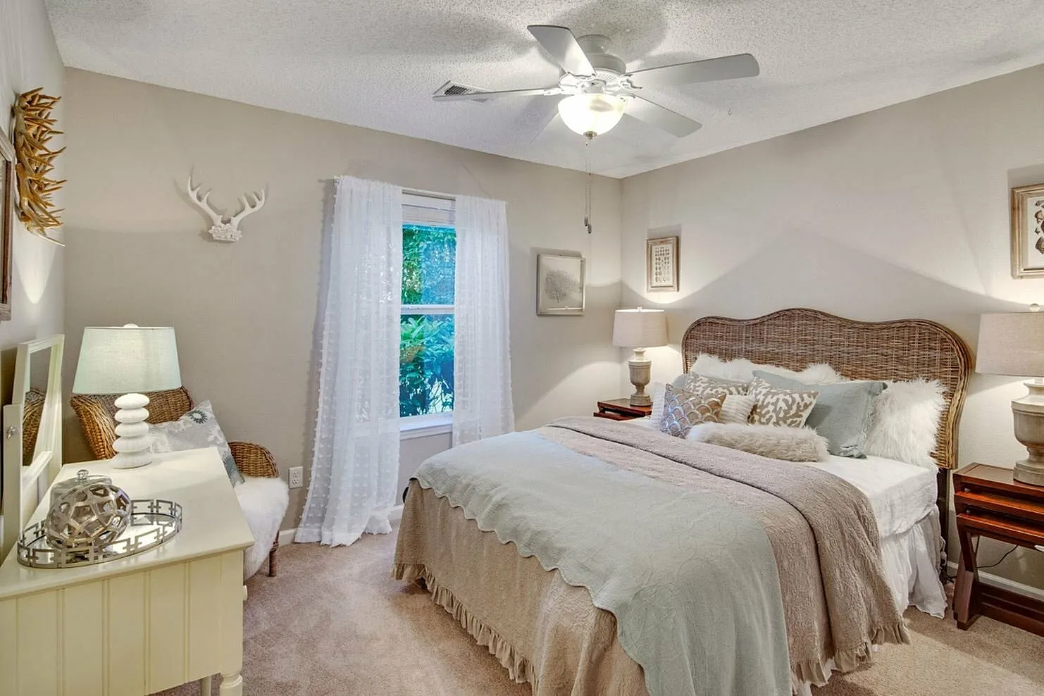 Charming bedroom retreat with wicker headboard, cozy layered bedding, and elegant decor in soft hues.