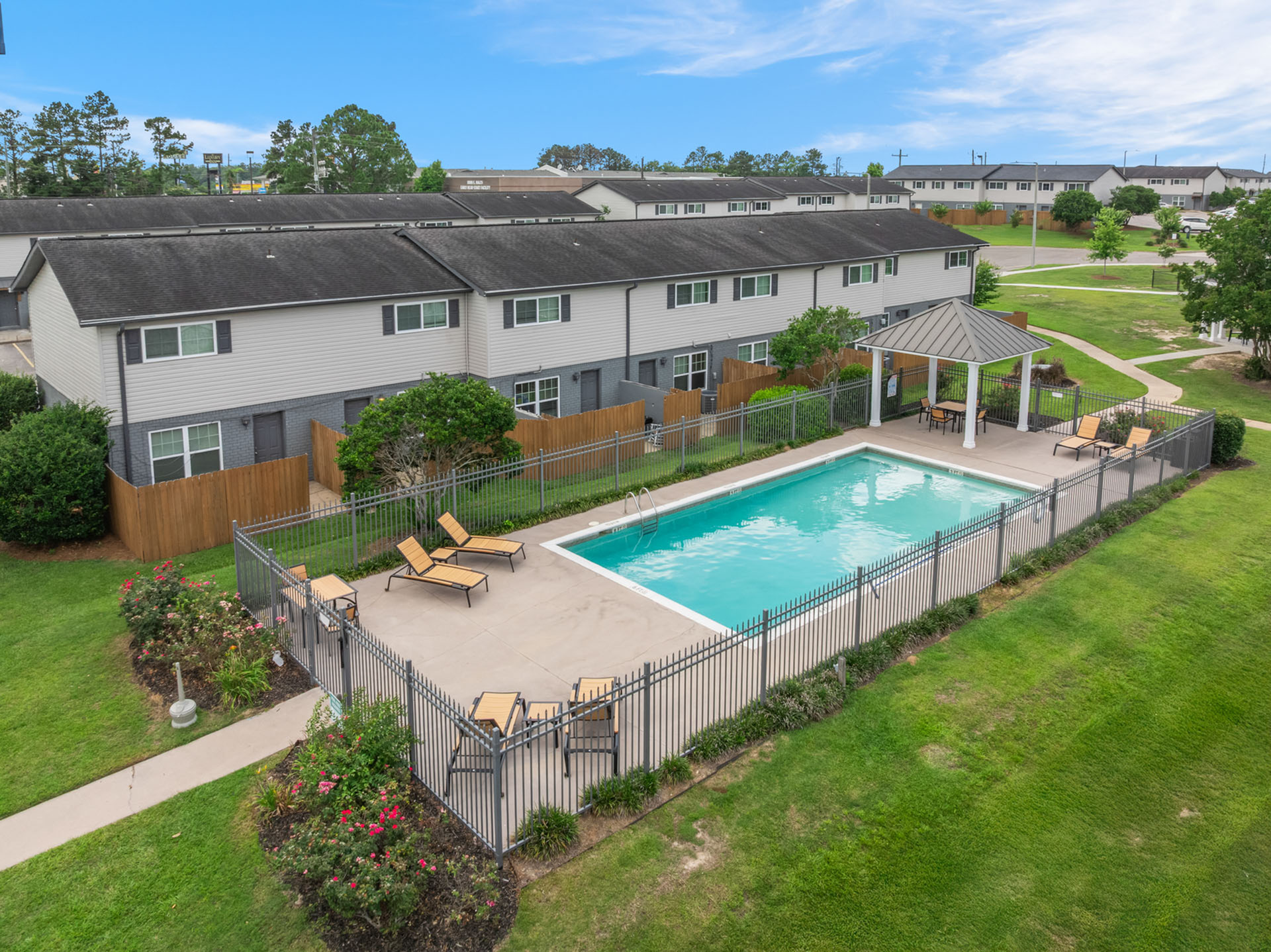 Inviting apartment community with a sparkling pool, elegant poolside loungers, and lush greenery, perfect for relaxation and community gatherings.