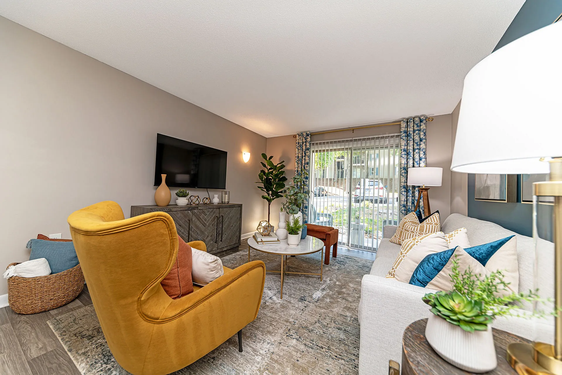 Elegant living room with modern decor, featuring a plush mustard armchair, stylish sofa, chic coffee table, and large windows with natural light.