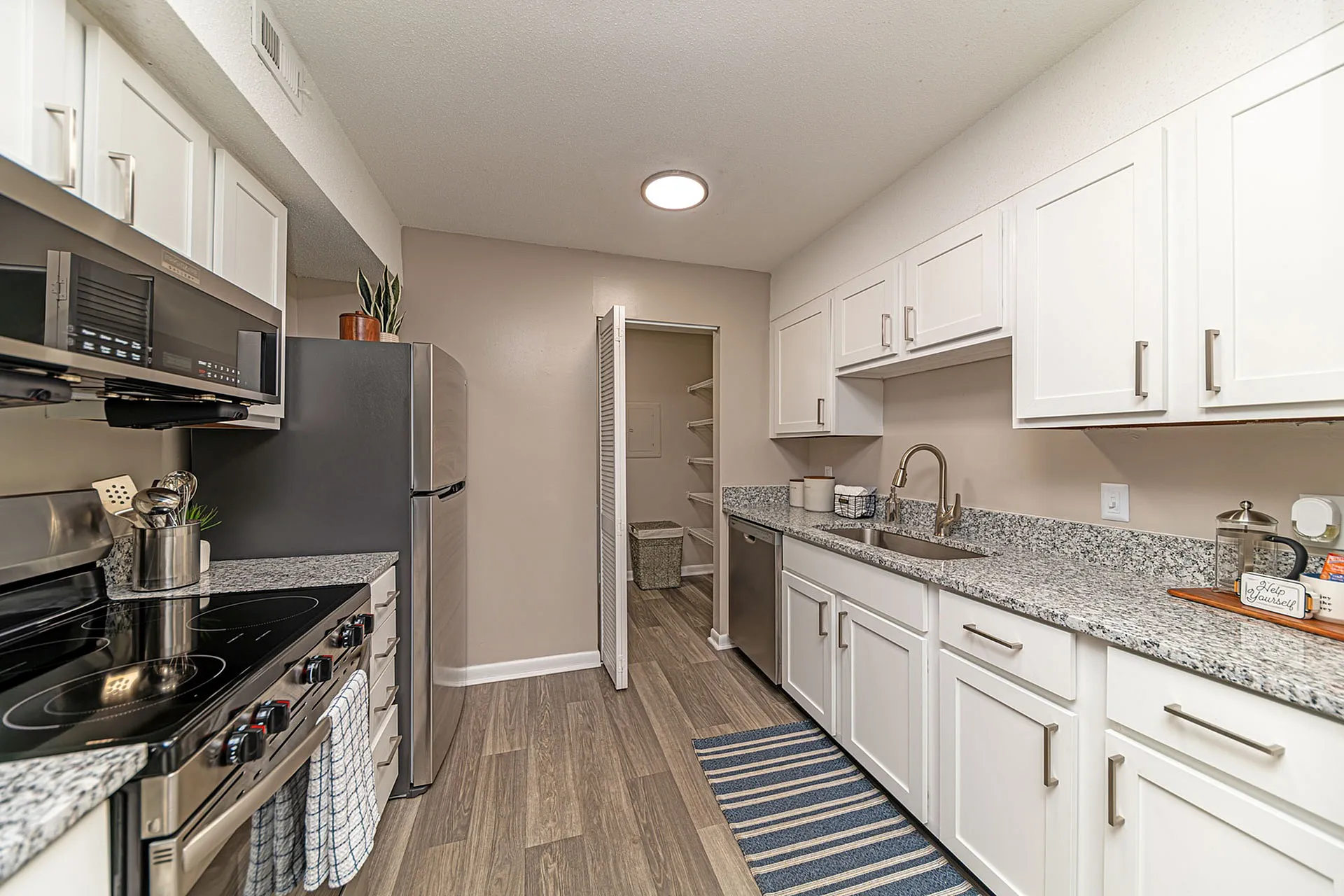 Modern kitchen with sleek stainless steel appliances, granite countertops, and white cabinetry, perfect for stylish culinary adventures.