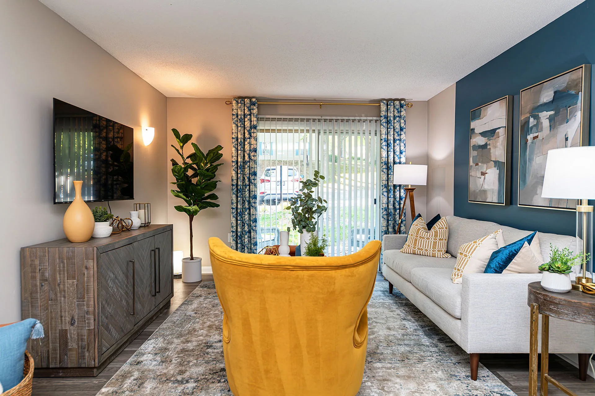 Contemporary living room featuring a vibrant mustard chair, cozy gray sofa, modern decor, and natural light streaming through elegant drapes.
