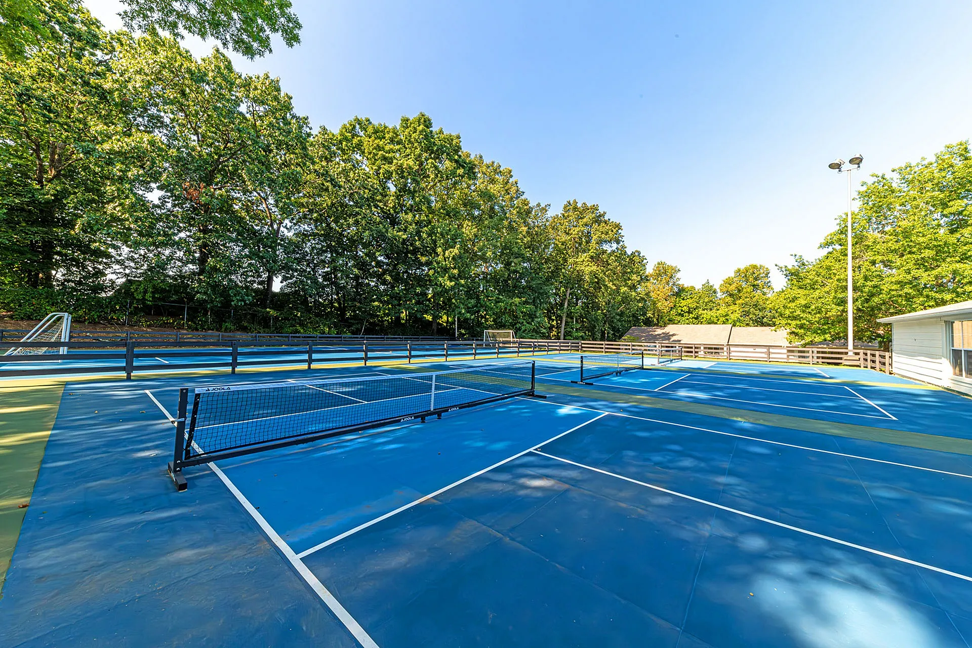 Vibrant outdoor tennis court surrounded by lush greenery, perfect for sports enthusiasts.