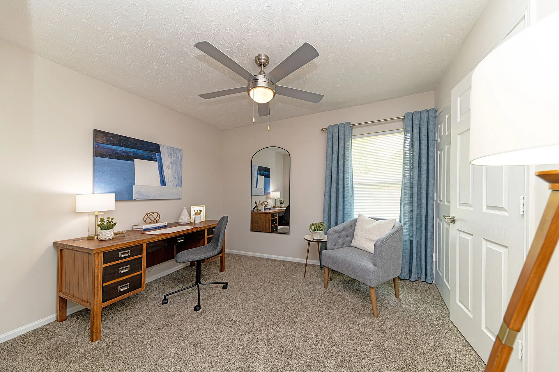 Chic home office featuring a stylish wooden desk, modern decor, and cozy seating with natural light enhancing the serene ambiance.