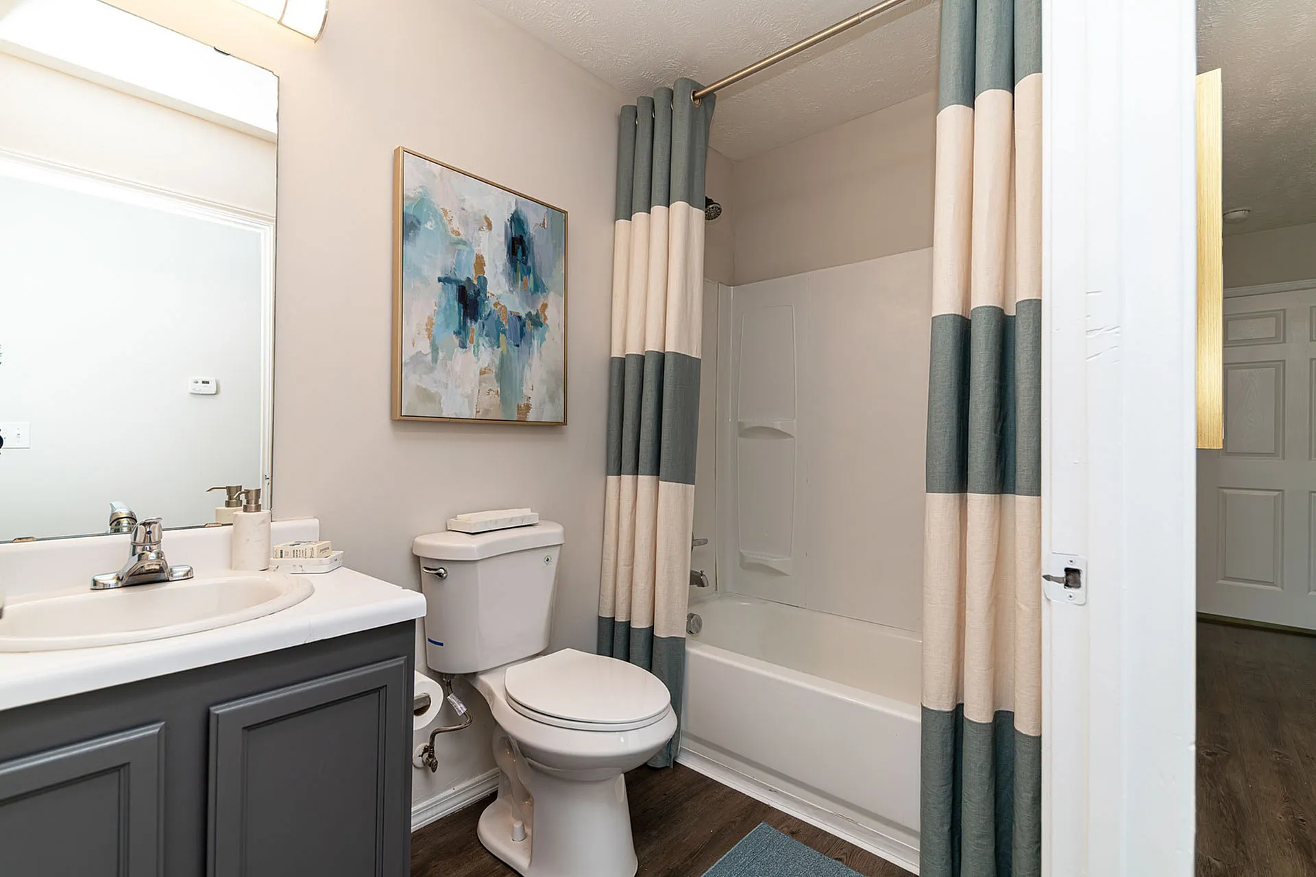 Modern bathroom with chic blue and beige curtains, stylish vanity, and contemporary artwork.
