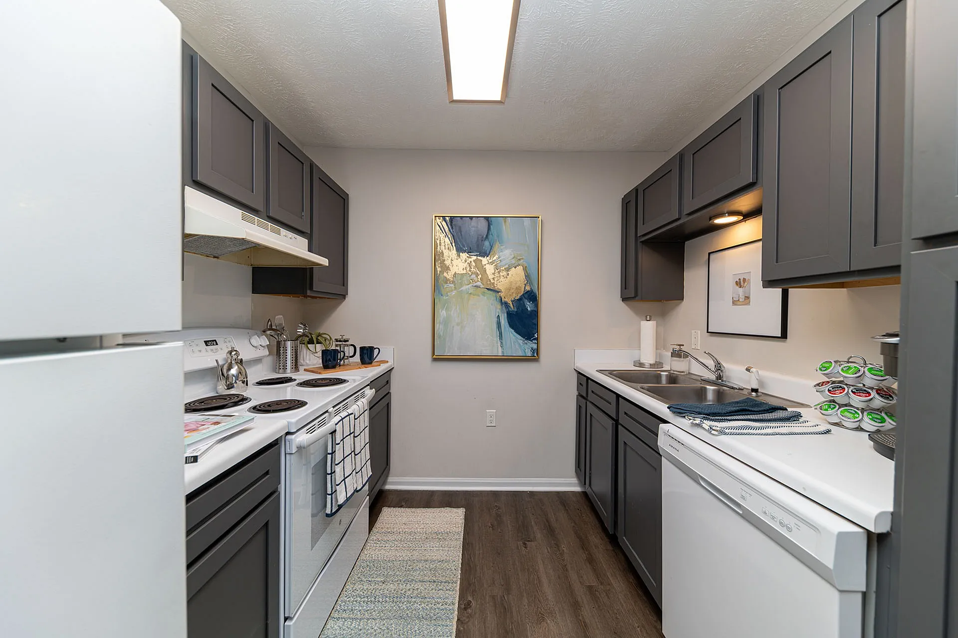 Modern kitchen with sleek gray cabinets, white appliances, and elegant decor, offering a stylish and functional space.