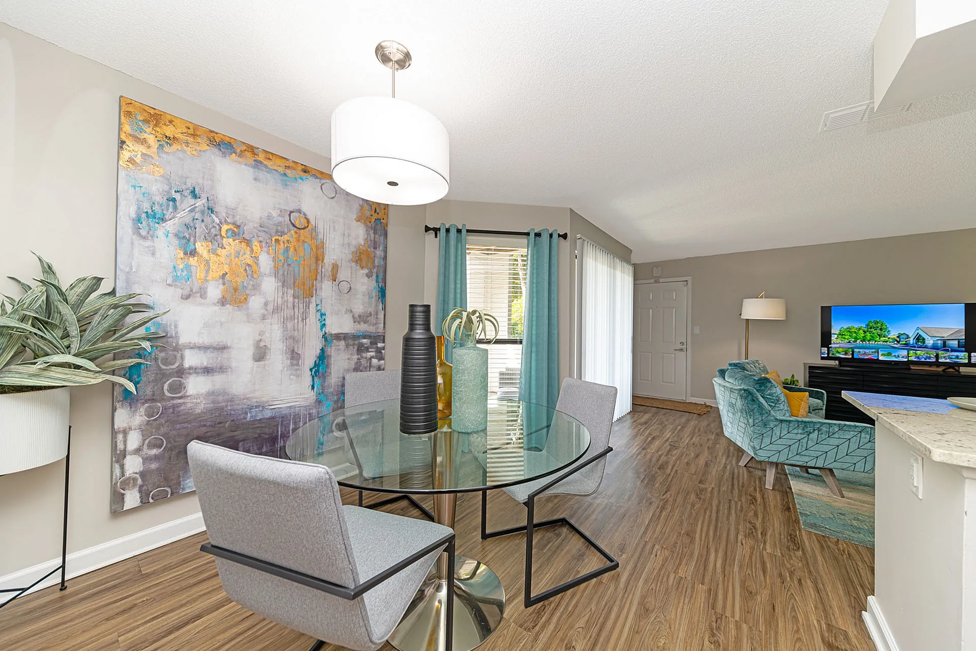 Chic and modern living area featuring a glass dining table with elegant seating, vibrant abstract art, and natural light streaming through large windows.
