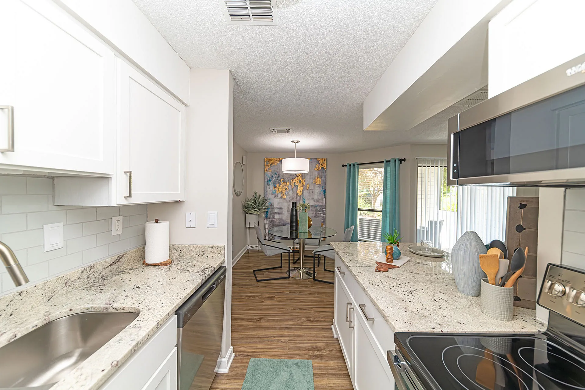 Bright, modern kitchen with granite countertops flowing into a cozy dining area with a stylish round table and natural light.