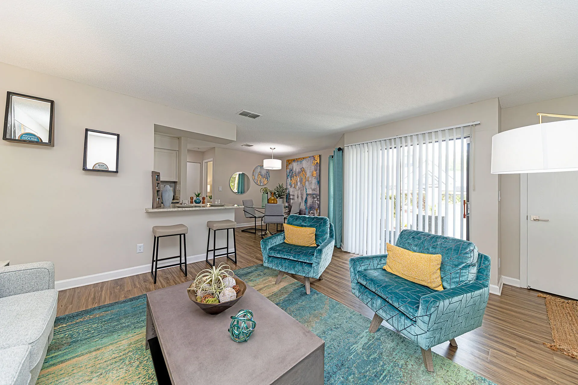 Contemporary living area with vibrant teal chairs, stylish decor, and an inviting open-concept design featuring natural light and elegant wood flooring.